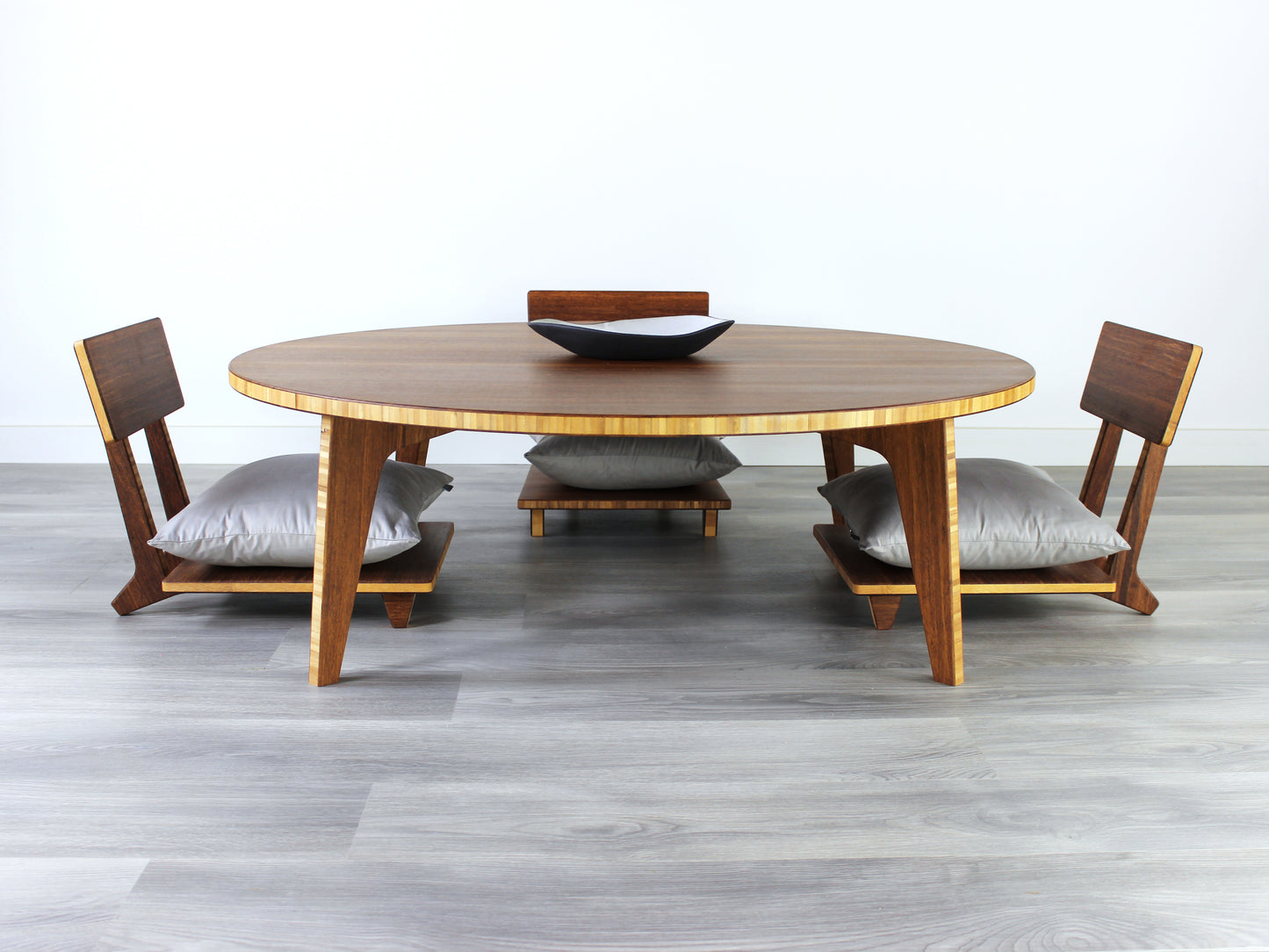 Large Circle Low Table with a chestnut bamboo finish and midcentury modern design. Three Floor Chair Comfort with grey pillows are set at the table. Small black pottery vessel placed on table top.
Japandi, minimalist, mid-century, Japanese inspired, modern, contemporary, clean lines, organic design, sustainable bamboo, renewable bamboo, solid bamboo, eco-friendly furniture, natural materials, natural-based finish