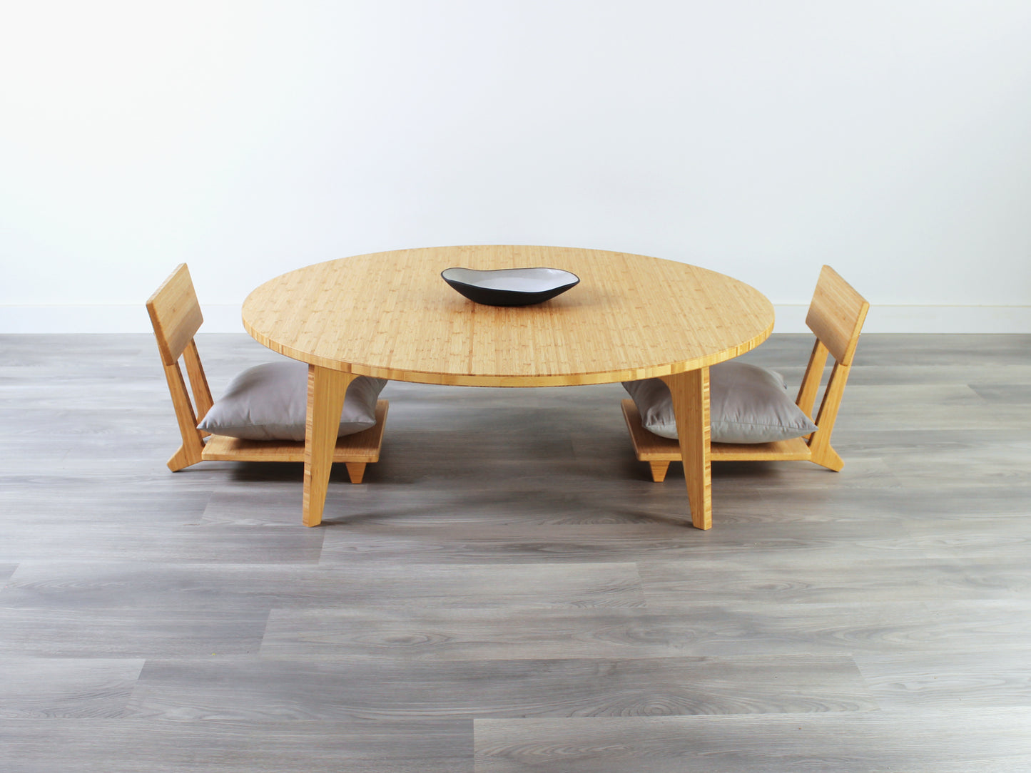 Large Circle Low Table with a natural bamboo finish and midcentury modern design. Two Floor Chair Comfort with grey pillows are set at the table. Small black pottery vessel placed on table top.
Japandi, minimalist, mid-century, Japanese inspired, modern, contemporary, clean lines, organic design, sustainable bamboo, renewable bamboo, solid bamboo, eco-friendly furniture, natural materials, natural-based finish