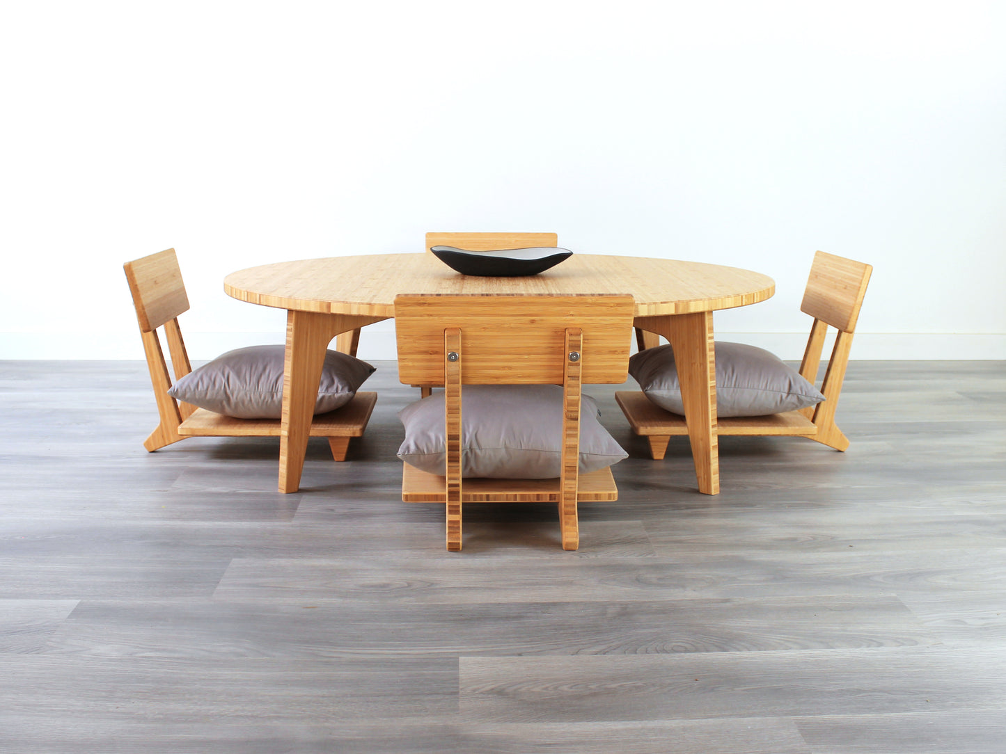 Large Circle Low Table with a natural bamboo finish and midcentury modern design. Four Floor Chair Comfort with grey pillows are set at the table. Small black pottery vessel placed on table top.
Japandi, minimalist, mid-century, Japanese inspired, modern, contemporary, clean lines, organic design, sustainable bamboo, renewable bamboo, solid bamboo, eco-friendly furniture, natural materials, natural-based finish