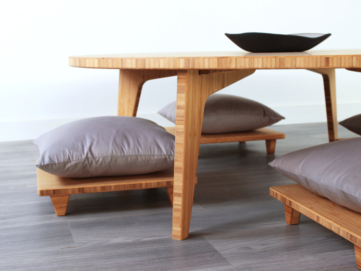 Large Circle Low Table with a natural bamboo finish and midcentury modern design. Four Floor Chair Comfort with grey pillows are set at the table. Small black pottery vessel placed on table top.
Japandi, minimalist, mid-century, Japanese inspired, modern, contemporary, clean lines, organic design, sustainable bamboo, renewable bamboo, solid bamboo, eco-friendly furniture, natural materials, natural-based finish