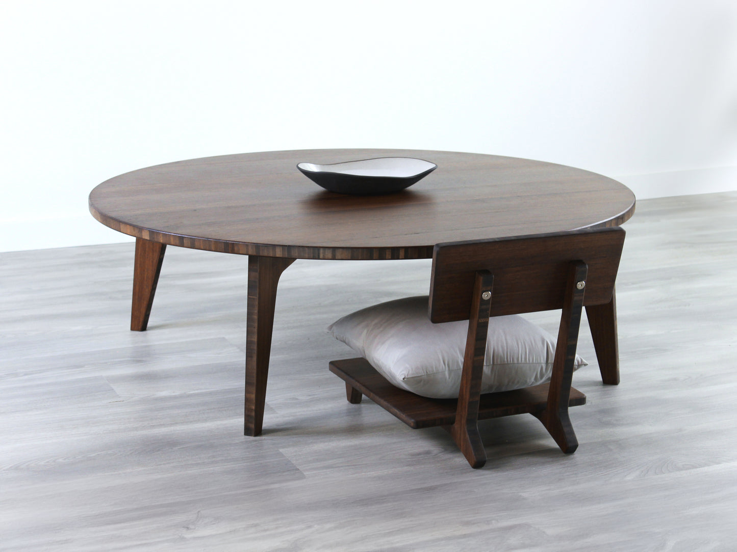 Large Circle Low Table with a walnut bamboo finish and midcentury modern design. A Floor Chair Comfort with a grey pillow are set at the table. Small black pottery vessel placed on table top.
Japandi, minimalist, mid-century, Japanese inspired, modern, contemporary, clean lines, organic design, sustainable bamboo, renewable bamboo, solid bamboo, eco-friendly furniture, natural materials, natural-based finish