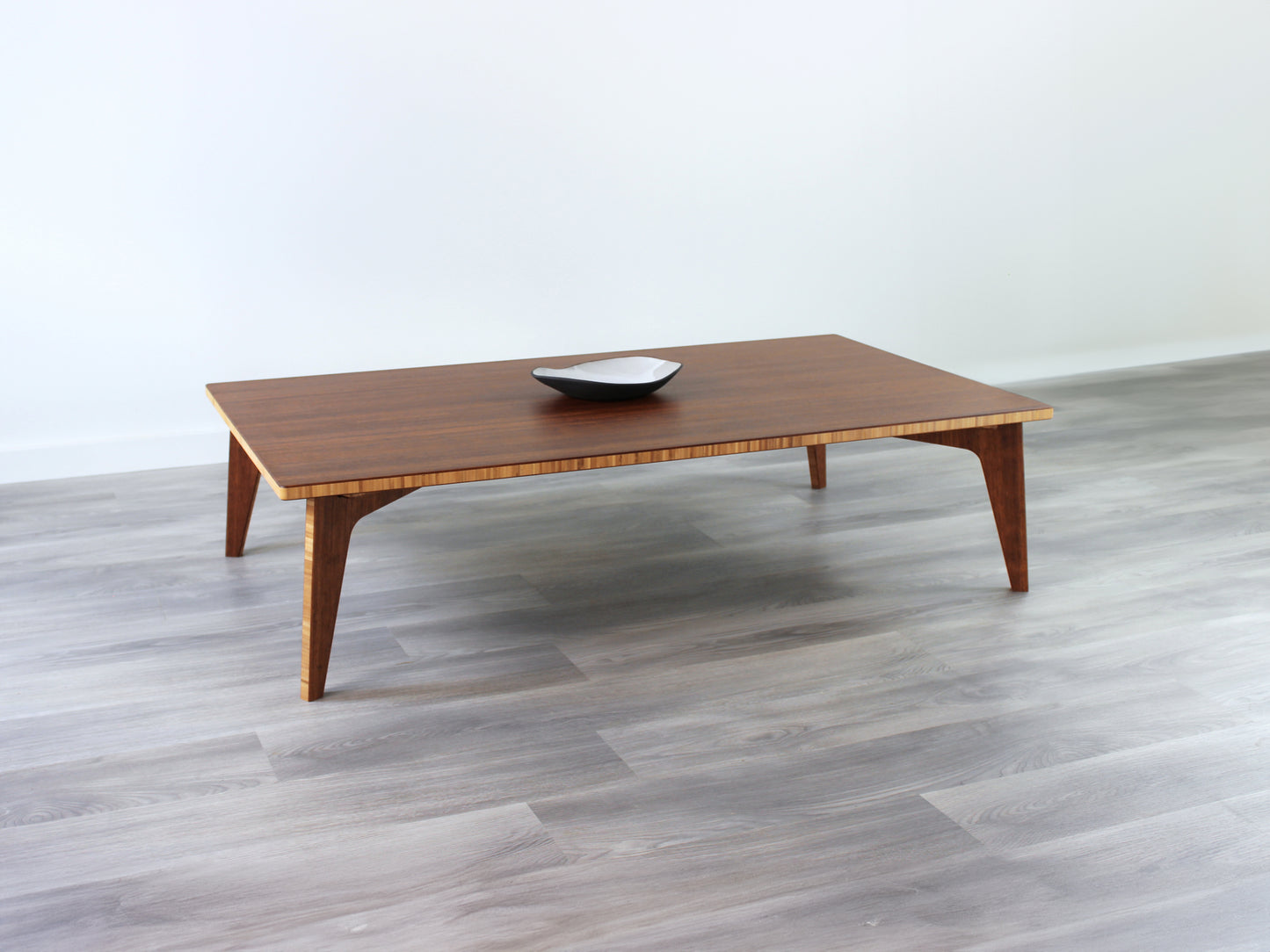 A large rectangular low table made of bamboo with a chestnut finish, placed on a grey floor with a white background. A black pottery vessel set on top of the table top.
japanese furniture
japanese low table
low coffee table
low dining table
low table
mid century
minimalist
minimalist table
modern