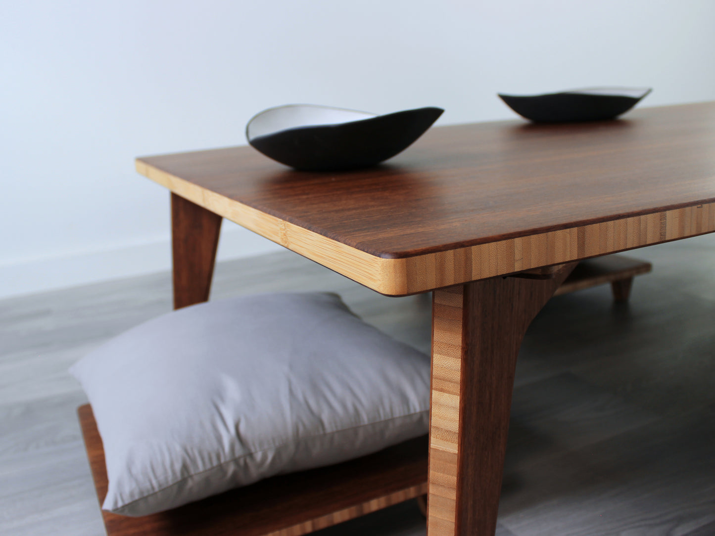 A large rectangular low table made of bamboo with a chestnut finish, placed on a grey floor with a white background. Two black pottery vessel set on top of the table top. Floor Chair Posture with grey pillows on top are placed underneath.
japanese furniture
japanese low table
low coffee table
low dining table
low table
mid century
minimalist
minimalist table
modern
posture support
floor chair
pillow lift