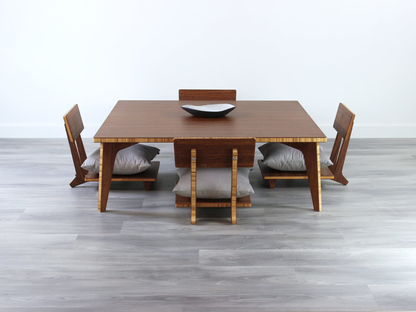 Large Square Low Table with a chestnut bamboo finish and midcentury modern design. Four Floor Chair Comfort with grey pillows are set at the table. Small black pottery vessel placed on table top.
Japandi, minimalist, mid-century, Japanese inspired, modern, contemporary, clean lines, organic design, sustainable bamboo, renewable bamboo, solid bamboo, eco-friendly furniture, natural materials, natural-based finish