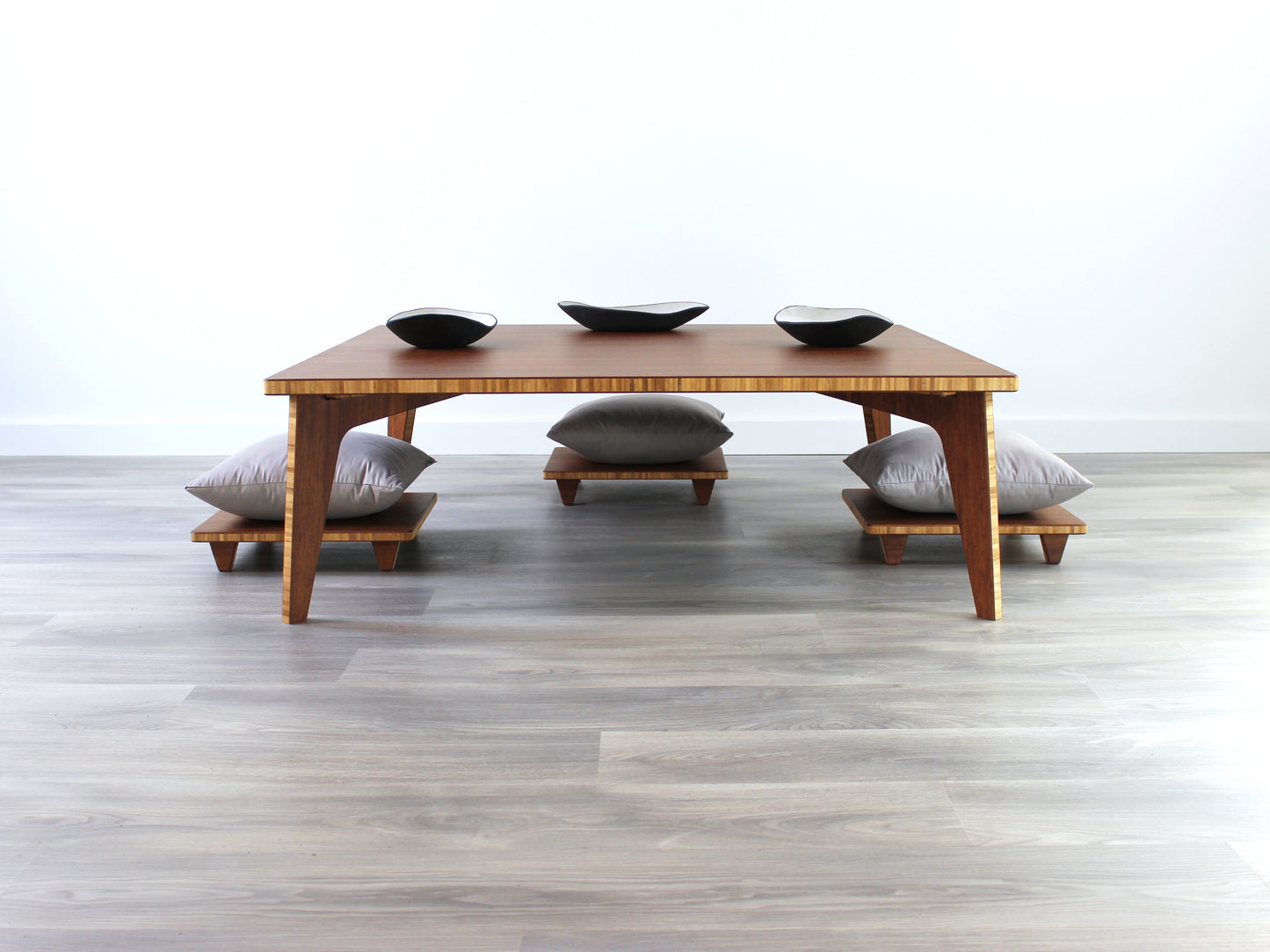 Large Square Low Table with a chestnut bamboo finish and midcentury modern design. Three Floor Chair Posture with grey pillows are set at the table. Small black pottery vessel placed on table top.
Japandi, minimalist, mid-century, Japanese inspired, modern, contemporary, clean lines, organic design, sustainable bamboo, renewable bamboo, solid bamboo, eco-friendly furniture, natural materials, natural-based finish