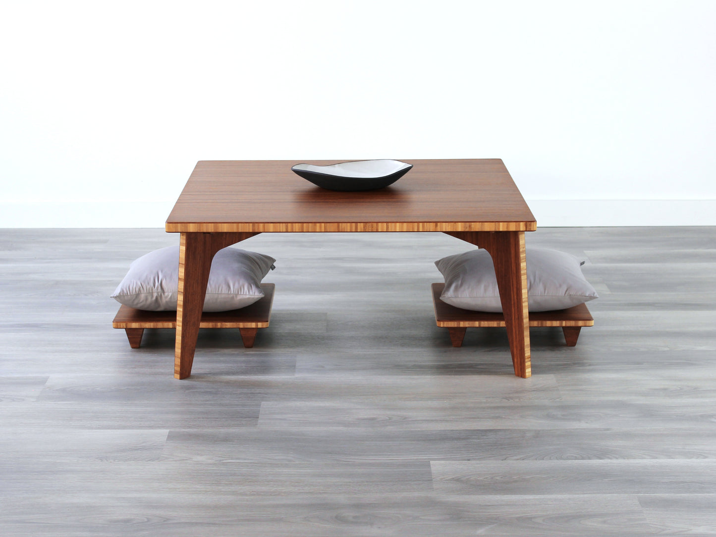 Small Square Table Set in chestnut finish. Two Floor Chair posture with grey pillows are placed below. A small black pottery vessel is placed on top of the table.
sustainable bamboo, renewable bamboo, solid bamboo, eco-friendly furniture, zero-waste, carbon neutral, natural materials, natural-based finish, repairable furniture