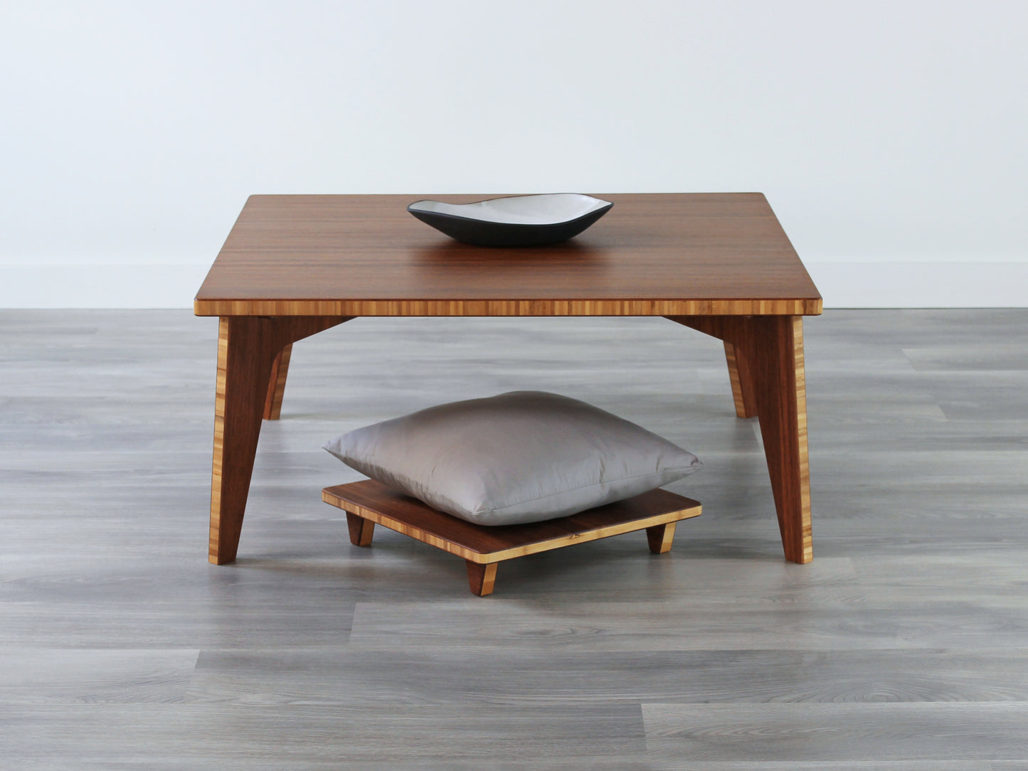 Small Square Table Set in chestnut finish. Two Floor Chair Posture are placed below. A small black pottery vessel is placed on top of the table.
sustainable bamboo, renewable bamboo, solid bamboo, eco-friendly furniture, zero-waste, carbon neutral, natural materials, natural-based finish, repairable furniture