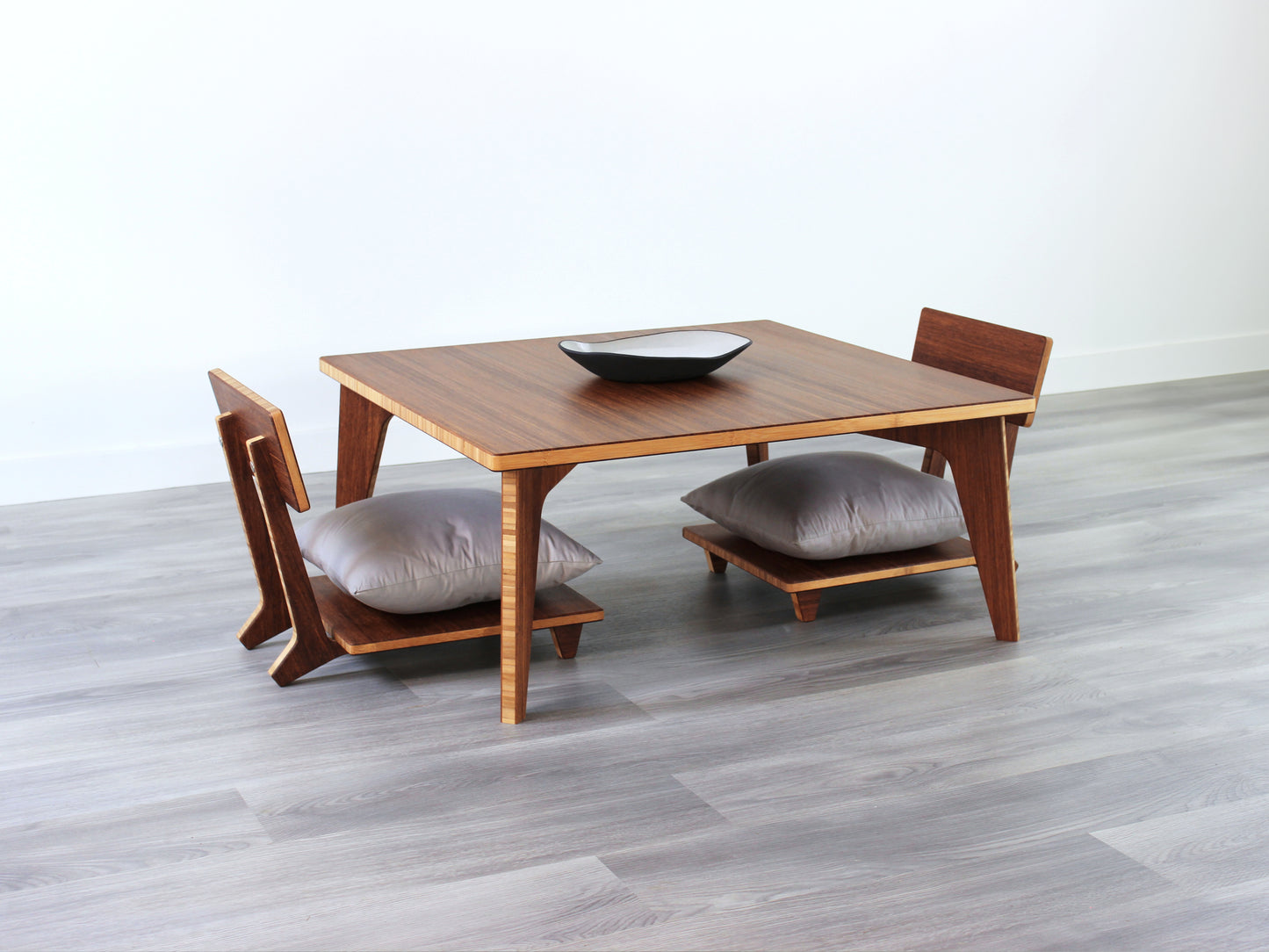 Small Square Table Set in chestnut finish. Two Floor Chair Comfort are placed below. A small black pottery vessel is placed on top of the table.
sustainable bamboo, renewable bamboo, solid bamboo, eco-friendly furniture, zero-waste, carbon neutral, natural materials, natural-based finish, repairable furniture