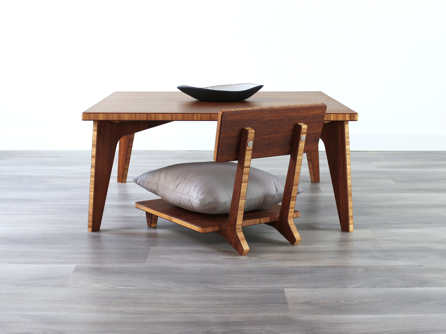 Small Square Table Set in chestnut finish. A Floor Chair Comfort is placed below. A small black pottery vessel is placed on top of the table.
sustainable bamboo, renewable bamboo, solid bamboo, eco-friendly furniture, zero-waste, carbon neutral, natural materials, natural-based finish, repairable furniture