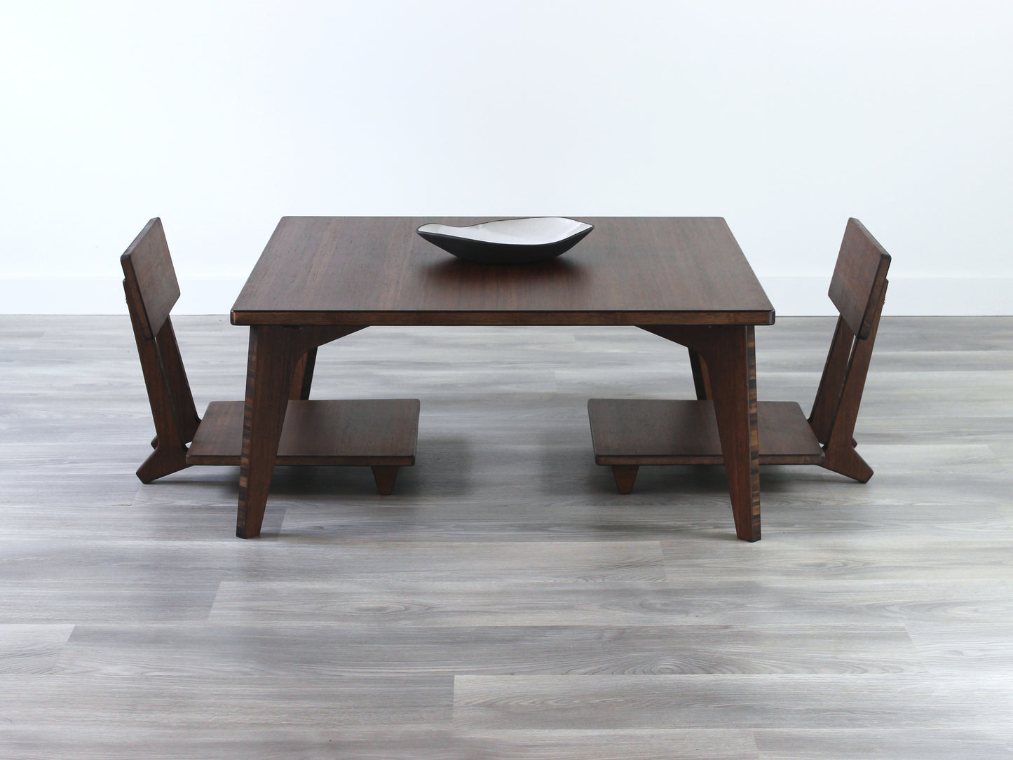 Small Square Table Set in walnut finish. Two Floor Chair Comfort are placed below. A small black pottery vessel is placed on top of the table.
sustainable bamboo, renewable bamboo, solid bamboo, eco-friendly furniture, zero-waste, carbon neutral, natural materials, natural-based finish, repairable furniture