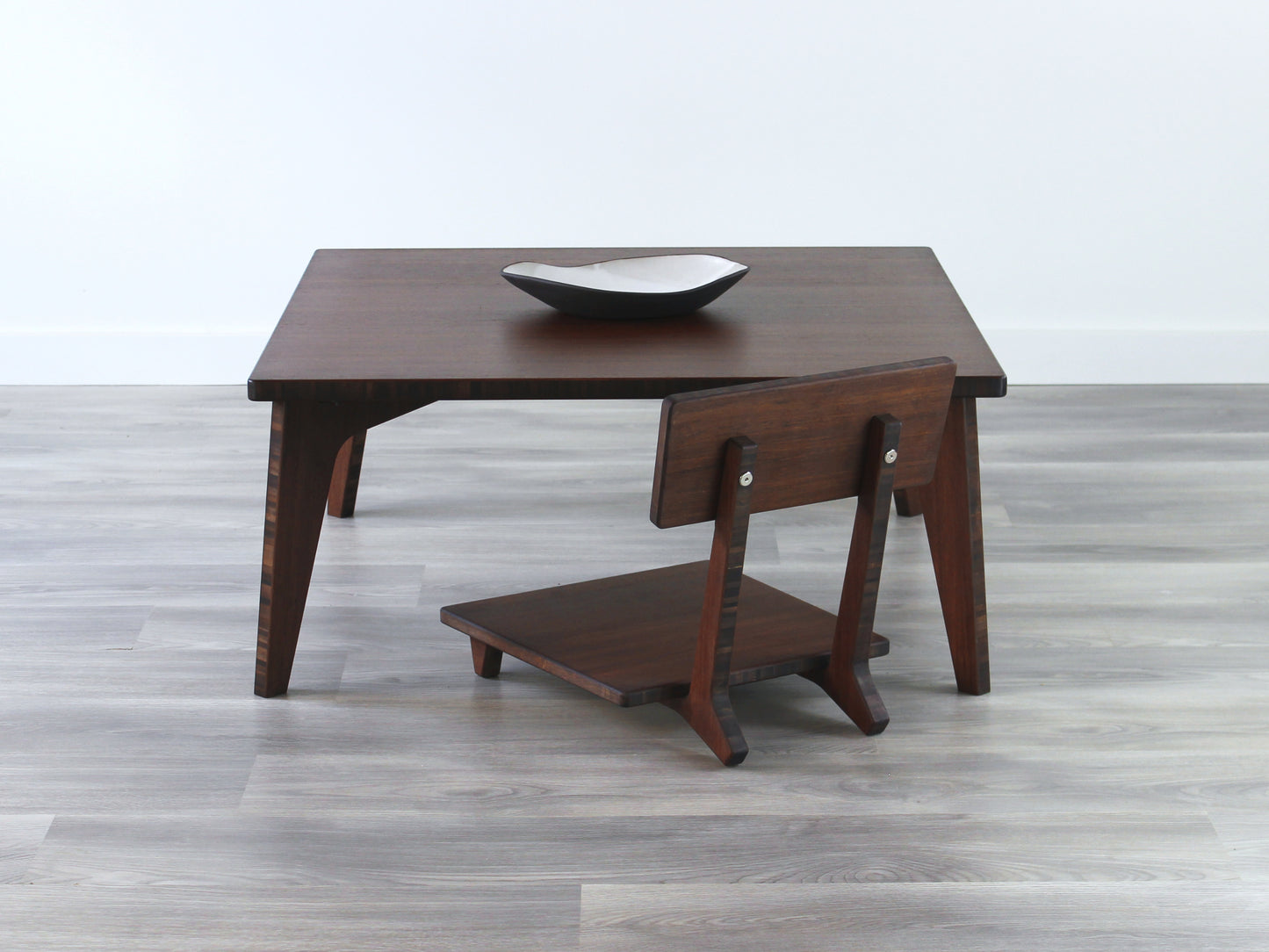 Small Square Table Set in walnut finish. A Floor Chair Comfort are placed below. A small black pottery vessel is placed on top of the table.
sustainable bamboo, renewable bamboo, solid bamboo, eco-friendly furniture, zero-waste, carbon neutral, natural materials, natural-based finish, repairable furniture
