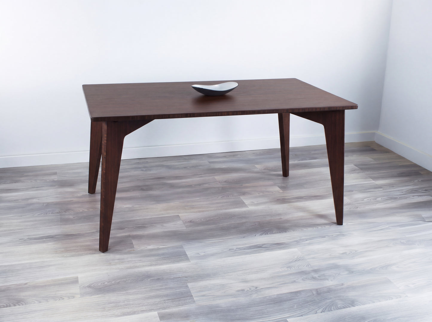 Bamboo dining table in a room with a light gray floor and white walls
