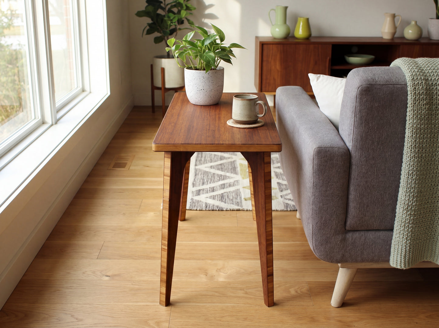 Living room with bamboo table, gray sofa, and plants near a window.

mid century
minimalist
side table
bamboo