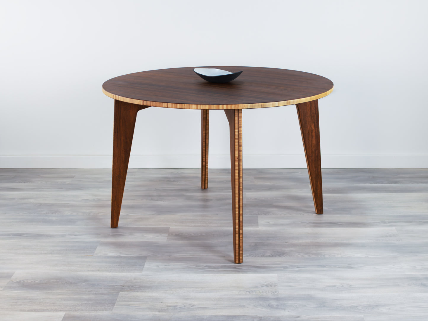 Bamboo dining table with a bowl on a gray floor and white wall background