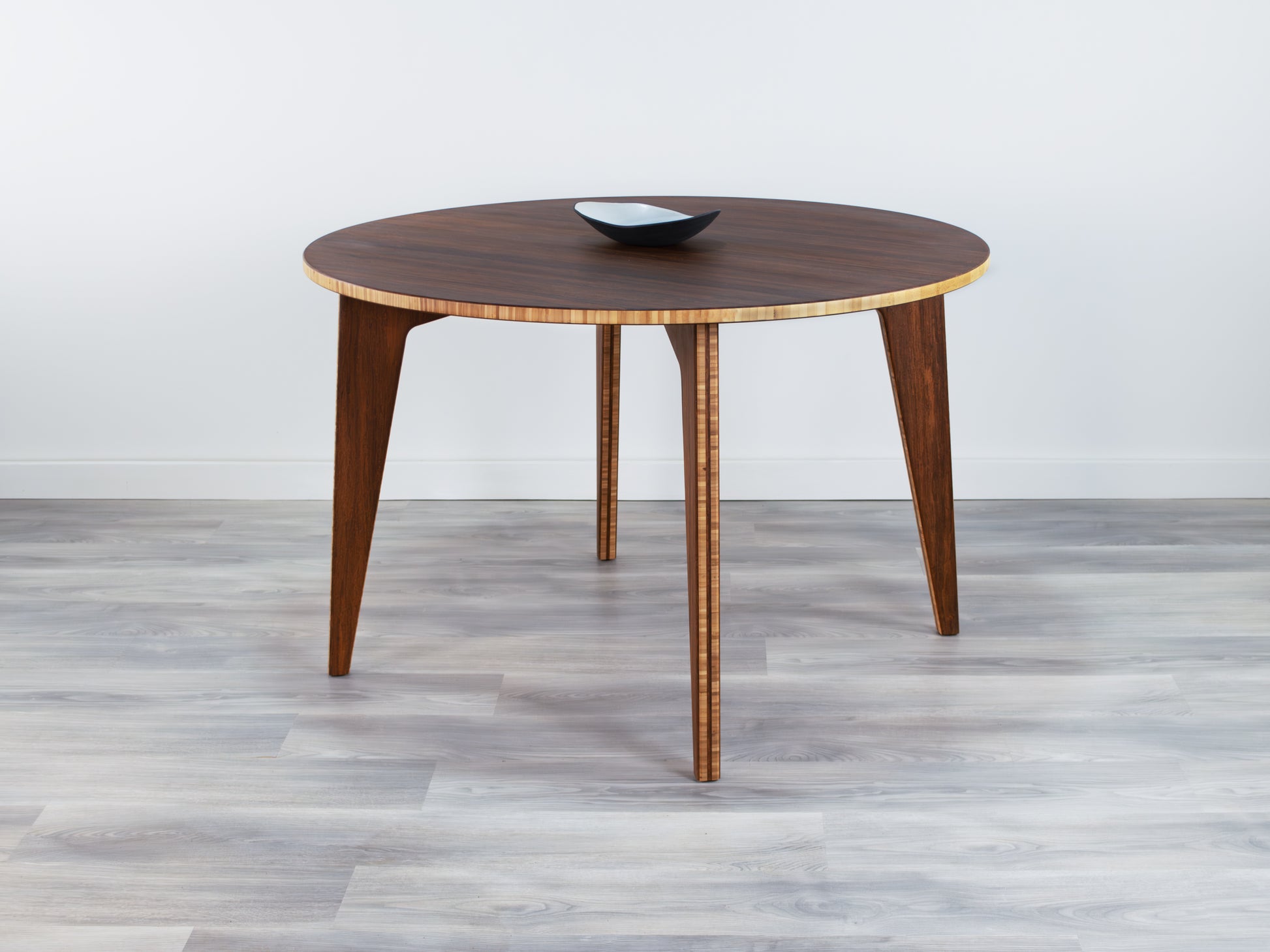 Bamboo dining table with a bowl on a gray floor and white wall background