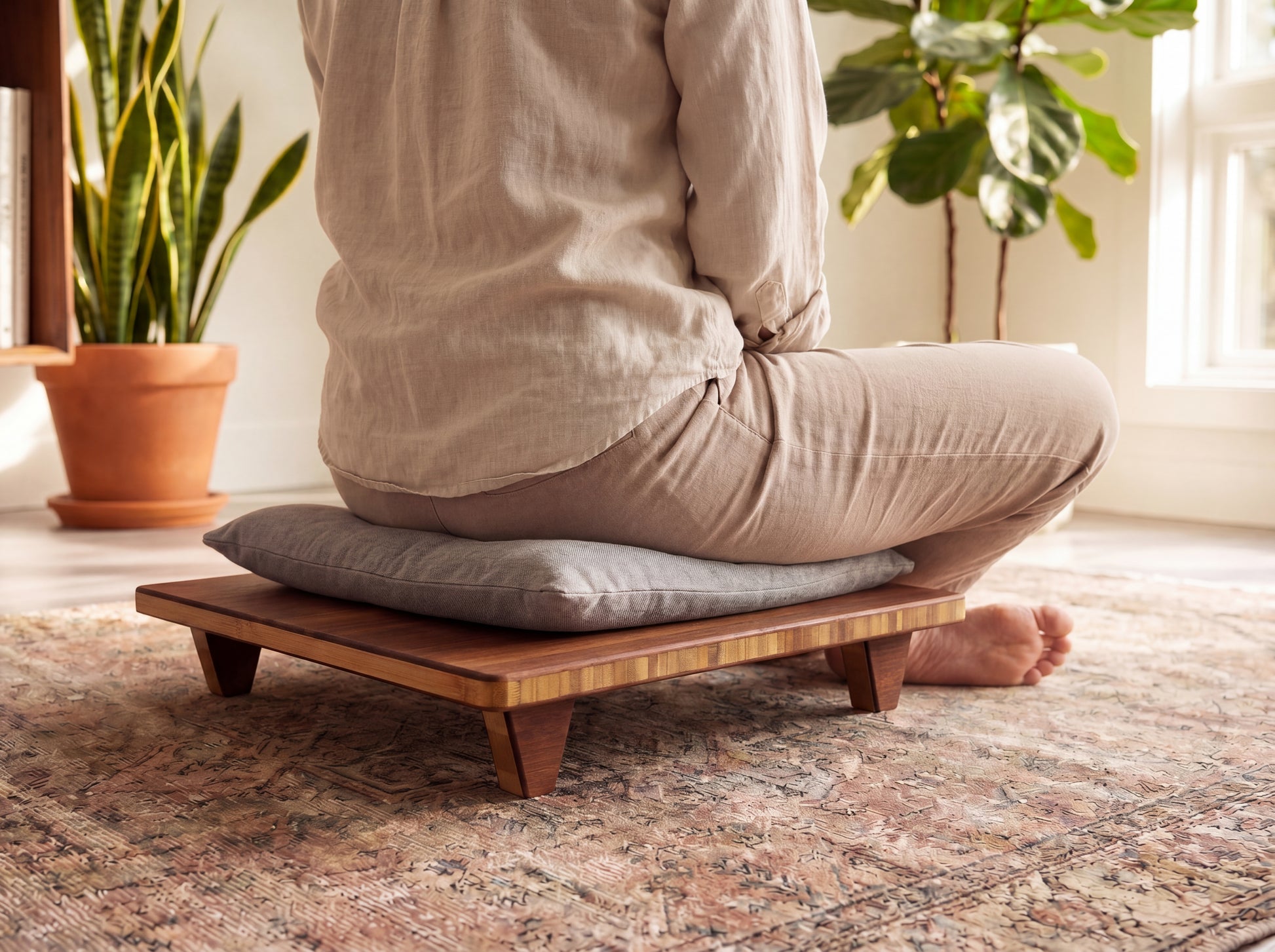 Person sitting on a bamboo meditation bench with cushion in a home setting.

Meditation Chair 
Japanese Tea Table 
Kotatsu
low chair
posture support 
ergonomic 
minimilist 

