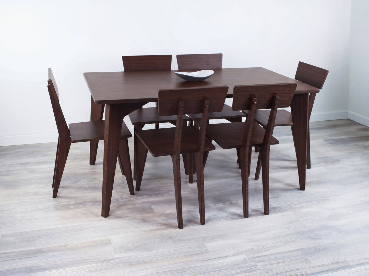 Bamboo dining table with six chairs in a minimalistic room.