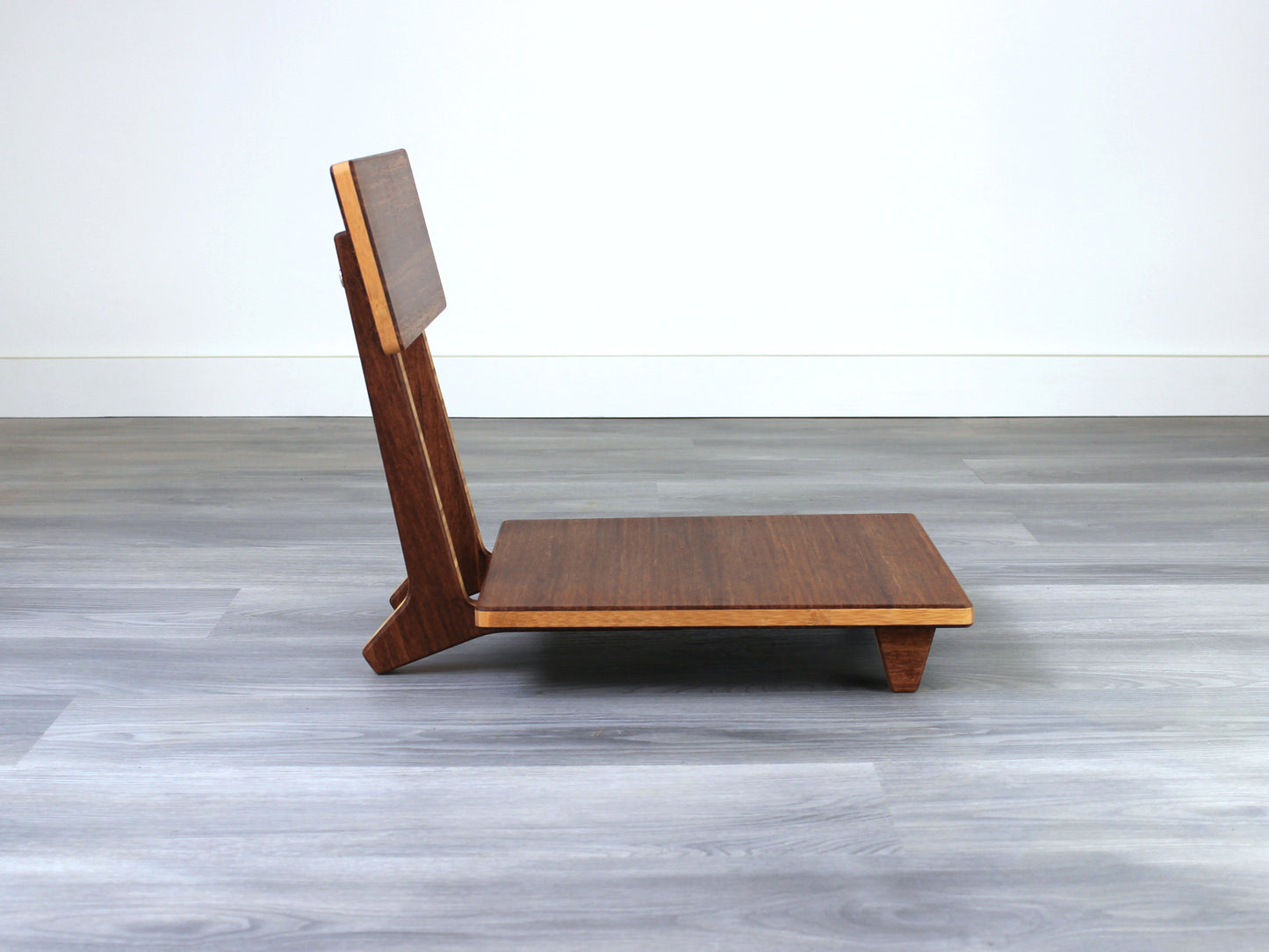 Chestnut bamboo Floor Chair Comfort with a square seat and a vertical supporting structure, displayed on a grey floor and white wall behind. 

floor chair
chabudai
contemporary
low seating 
floor chair with back 
ergonomic 