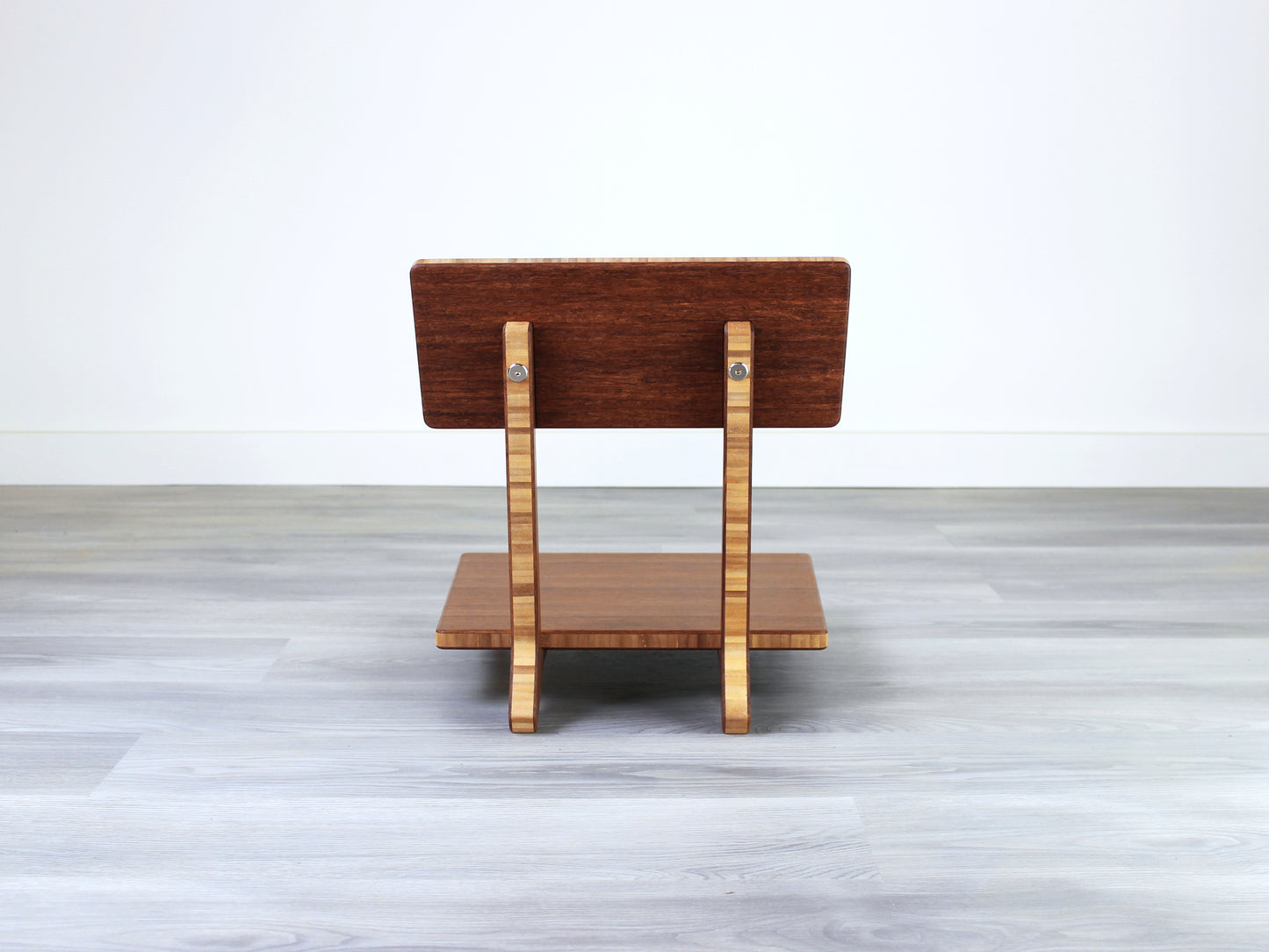Chestnut bamboo Floor Chair Comfort with a square seat and a vertical supporting structure, displayed on a grey floor and white wall behind. 

floor chair
chabudai
contemporary
low seating 
floor chair with back 
ergonomic 