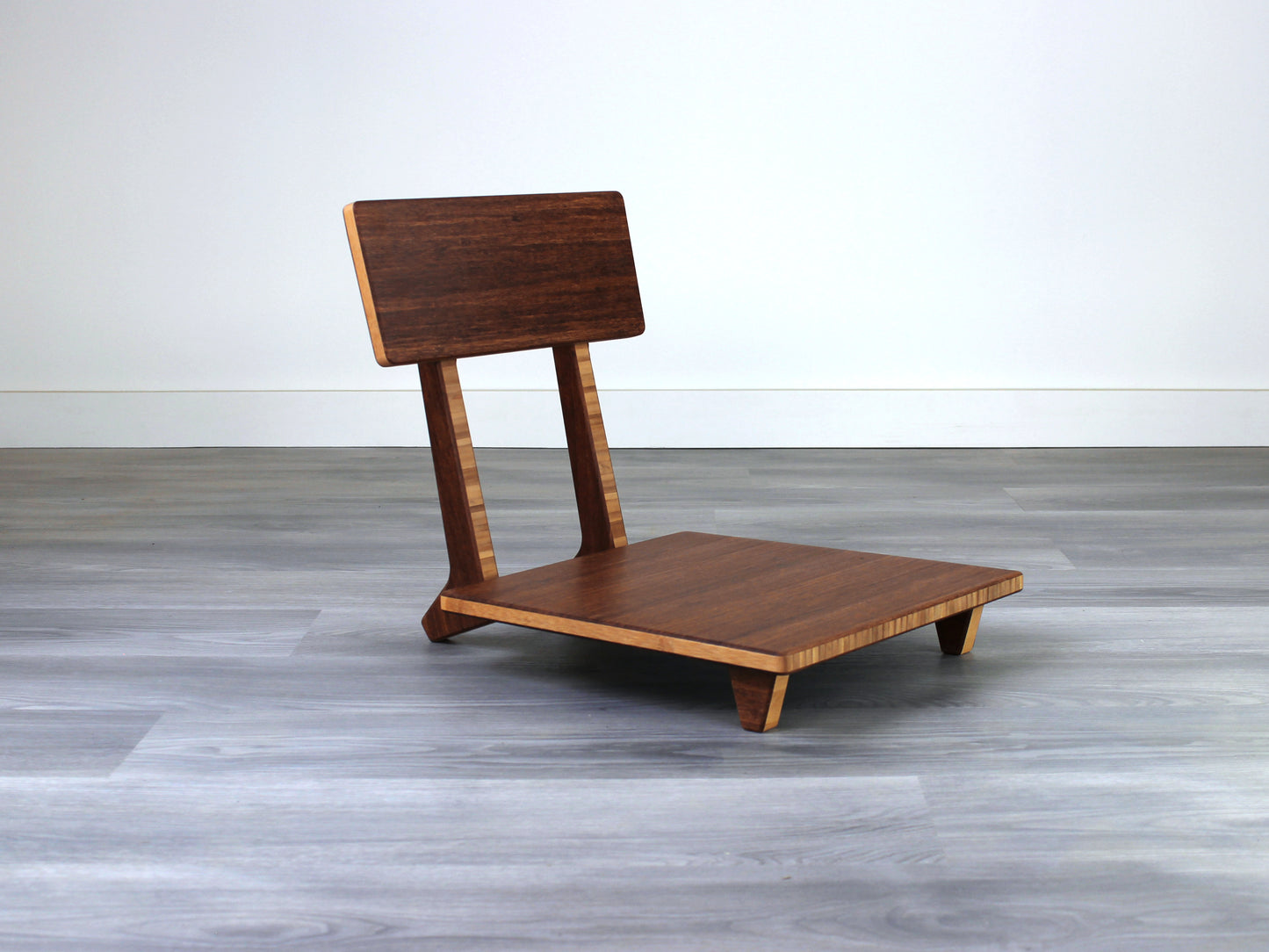 Chestnut bamboo Floor Chair Comfort with a square seat and a vertical supporting structure, displayed on a grey floor and white wall behind. 

floor chair
chabudai
contemporary
low seating 
floor chair with back 
ergonomic 