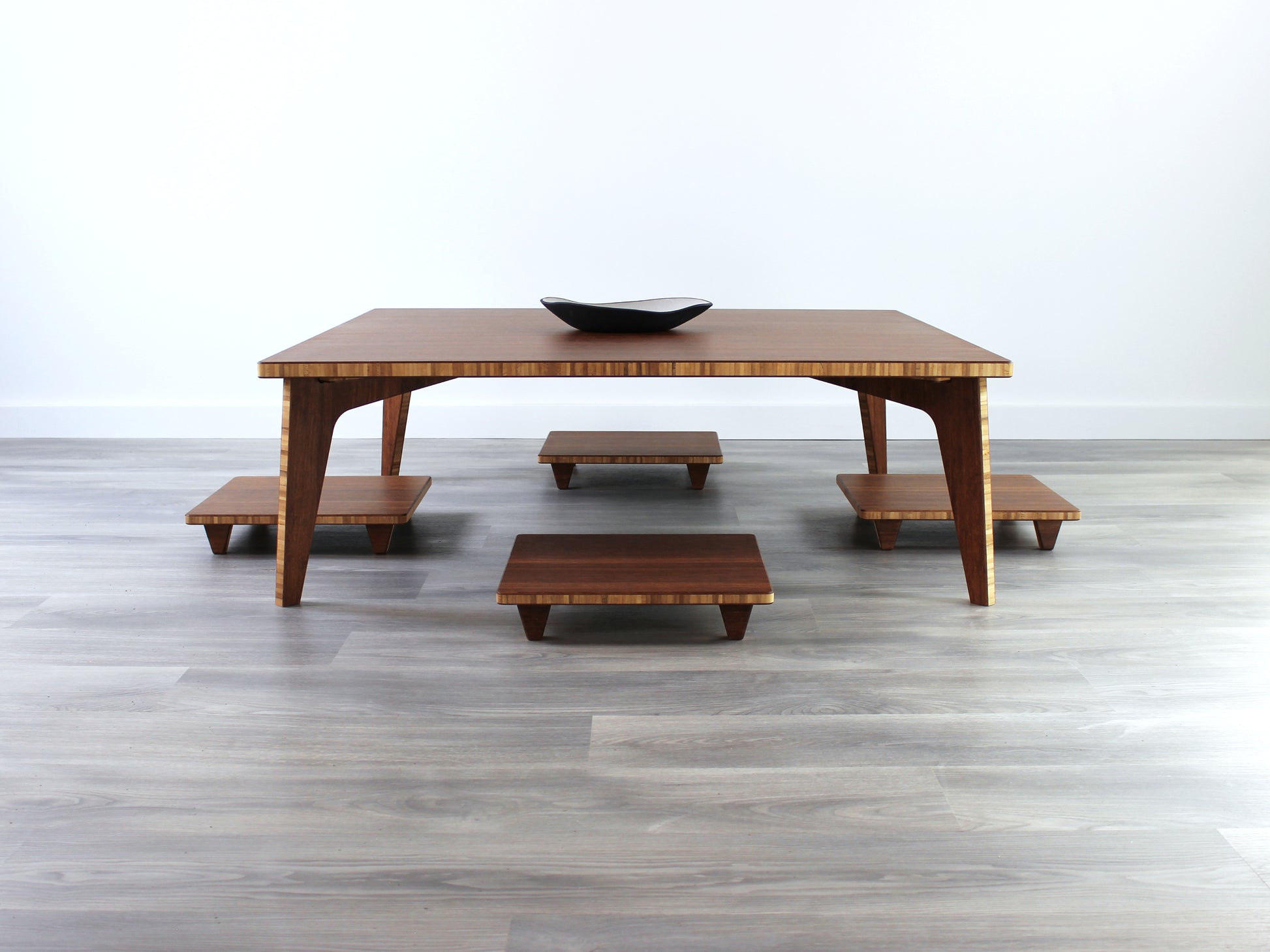 Chestnut Floor Chair Posture, four are placed on a grey floor and a white wall background, underneath a LOW table.

Meditation Chair 
Japanese Tea Table 
Kotatsu
low chair
posture support 
ergonomic 
minimilist