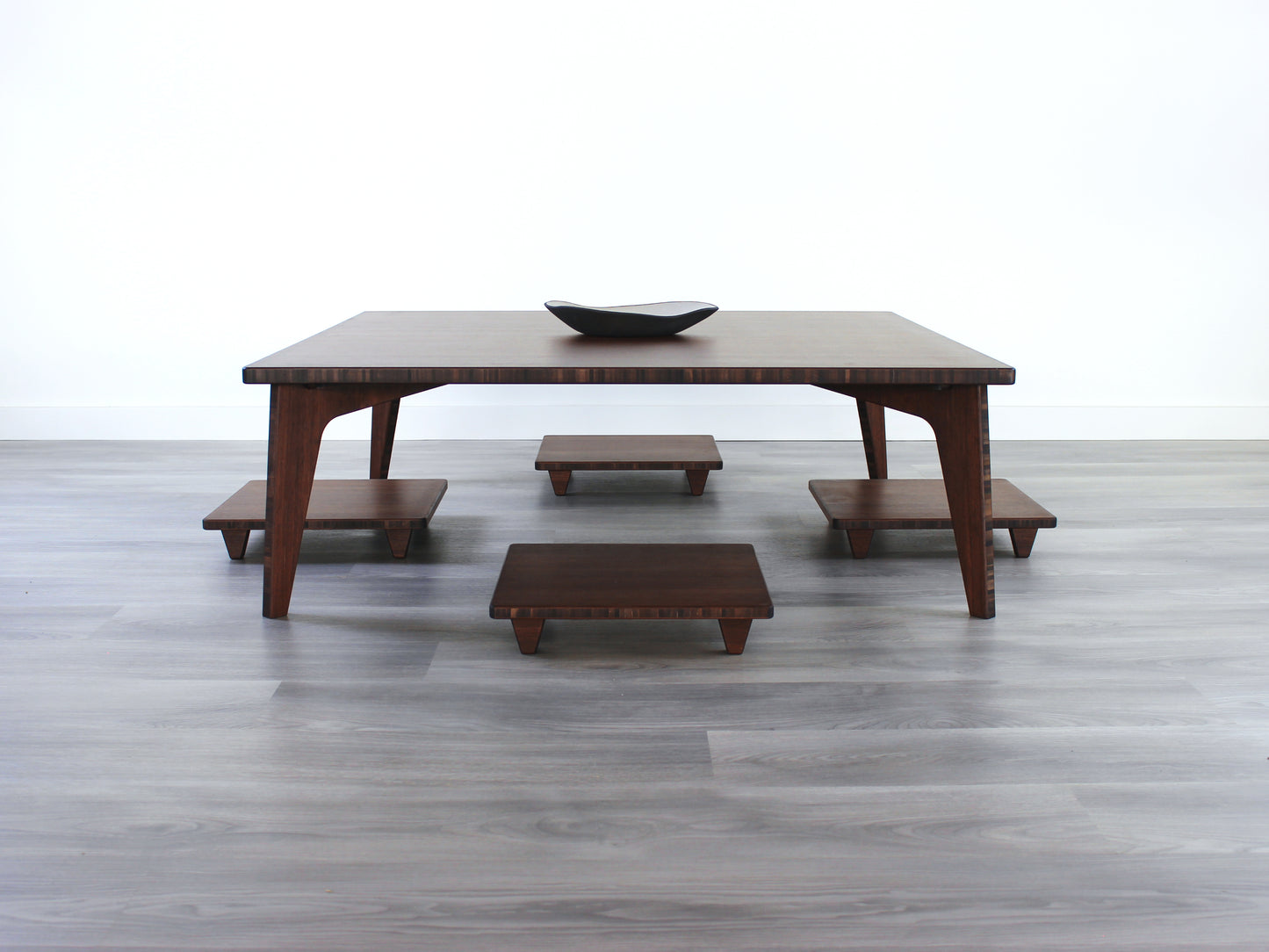 Walnut Floor Chair Posture, four are placed on a grey floor and a white wall background, underneath a LOW table.

Meditation Chair 
Japanese Tea Table 
Kotatsu
low chair
posture support 
ergonomic 
minimilist