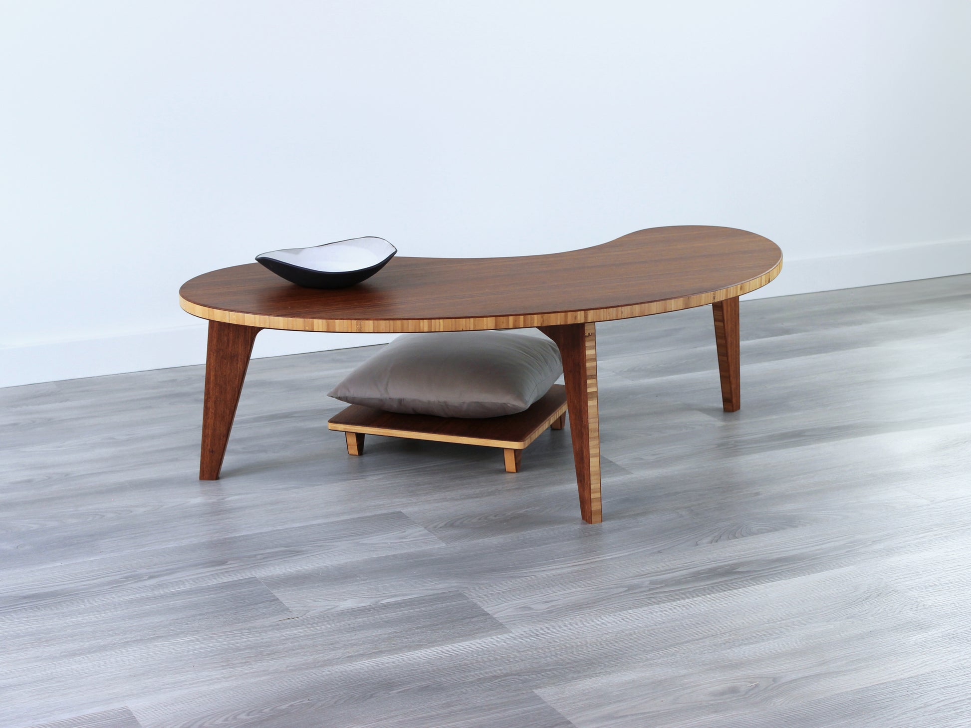 A Kidney LOW Table Set in chestnut bamboo, featuring a small black and white pottery vessel placed on top. Floor Chair Posture with a grey pillow set underneath. Placed on a Grey flooring with a white background. 

mid century modern low table
midcentury modern coffee table
floor table
japan coffee table
japan furniture
japan table
kidney coffee table 
bamboo low seating