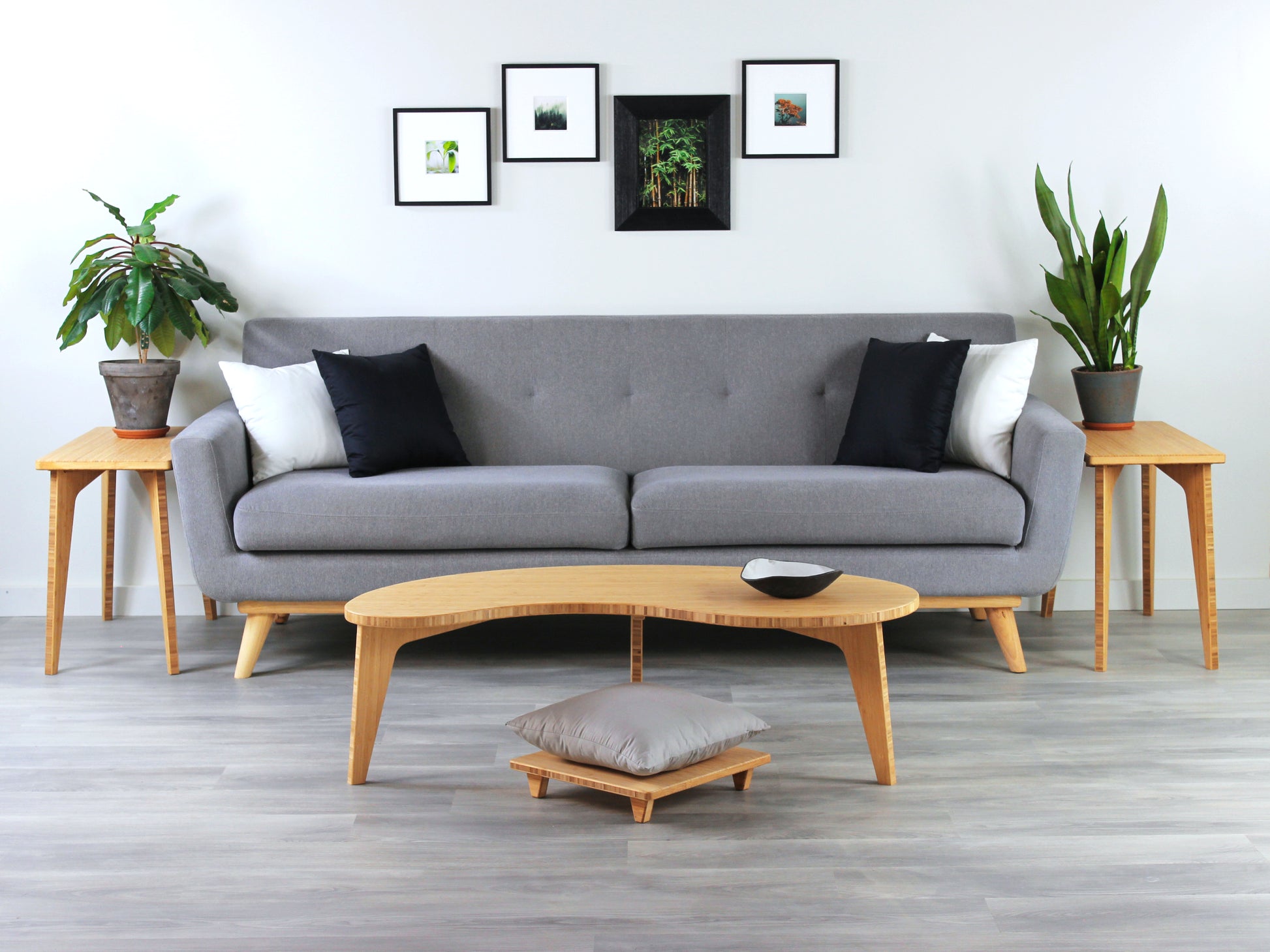 A Kidney LOW Table Set in natural bamboo, featuring a small black and white pottery vessel placed on top. Floor Chair posture with a grey pillow set underneath. Placed in a living room with grey flooring with a white background. Grey couch and houseplants on top of side tables in the background.

mid century modern low table
midcentury modern coffee table
floor table
japan coffee table
japan furniture
japan table
kidney coffee table 
bamboo low seating