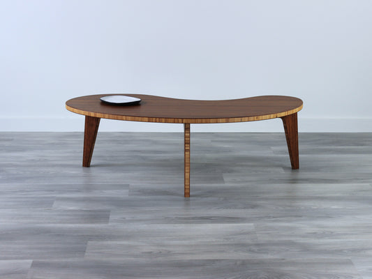 A small kidney-shaped chestnut bamboo table, featuring a small black and white pottery vessel placed on top. Grey flooring with a white background. 

mid century modern low table
midcentury modern coffee table
floor table
japan coffee table
japan furniture
japan table
kidney coffee table 
bamboo low table