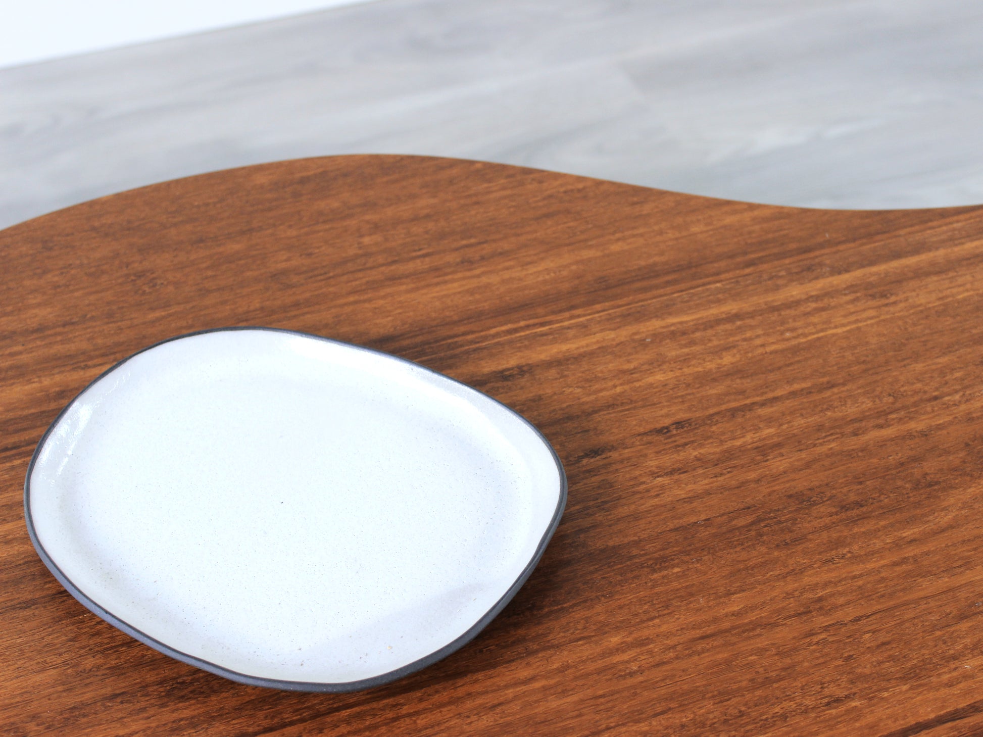 A small kidney-shaped chestnut bamboo table, featuring a small black and white pottery vessel placed on top. Grey flooring with a white background. 

mid century modern low table
midcentury modern coffee table
floor table
japan coffee table
japan furniture
japan table
kidney coffee table 
bamboo low table