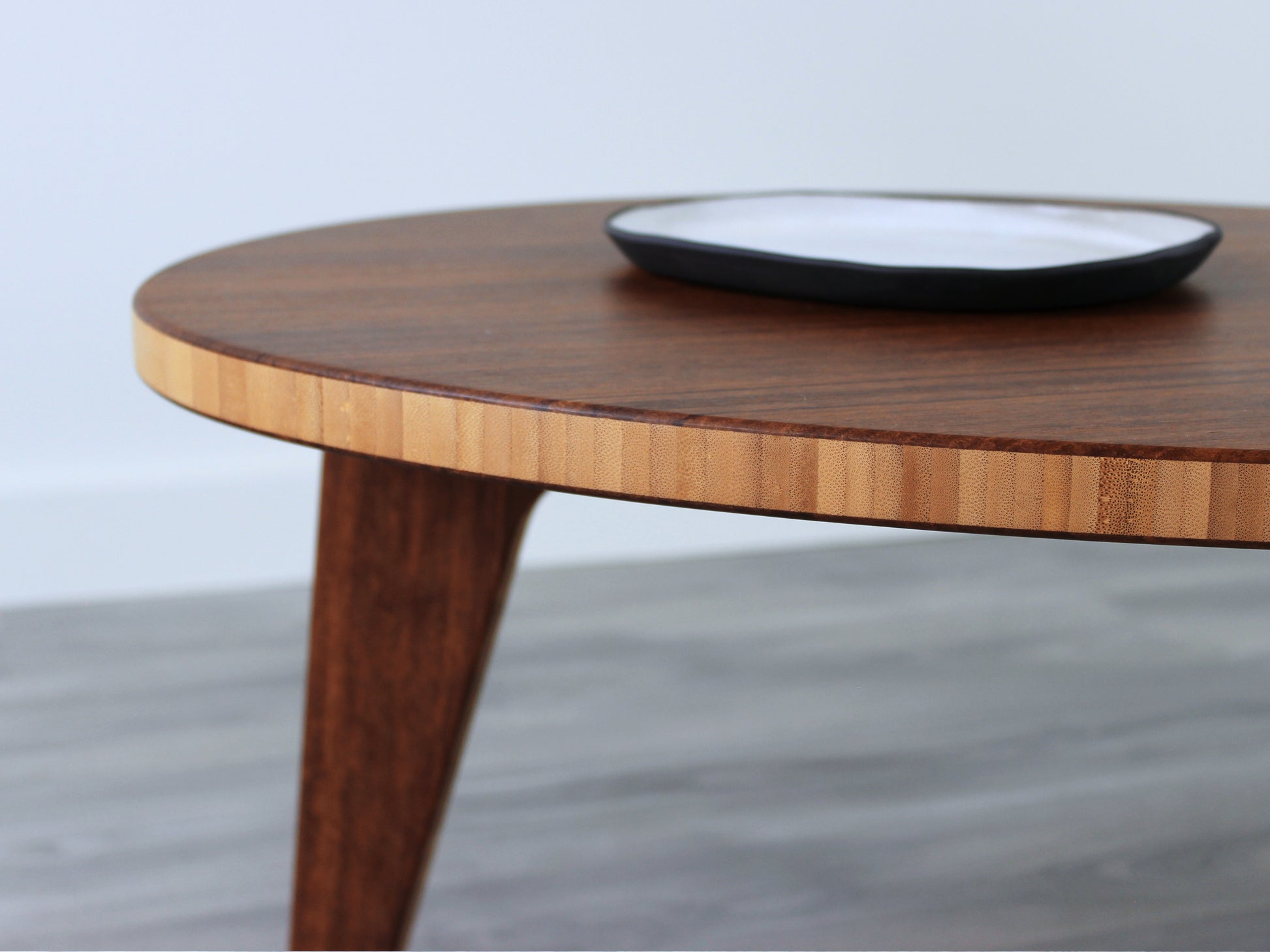 A kidney-shaped chestnut bamboo table, featuring a small black and white pottery vessel placed on top. Grey flooring with a white background. 

mid century modern low table
midcentury modern coffee table
floor table
japan coffee table
japan furniture
japan table
kidney coffee table 
bamboo low table