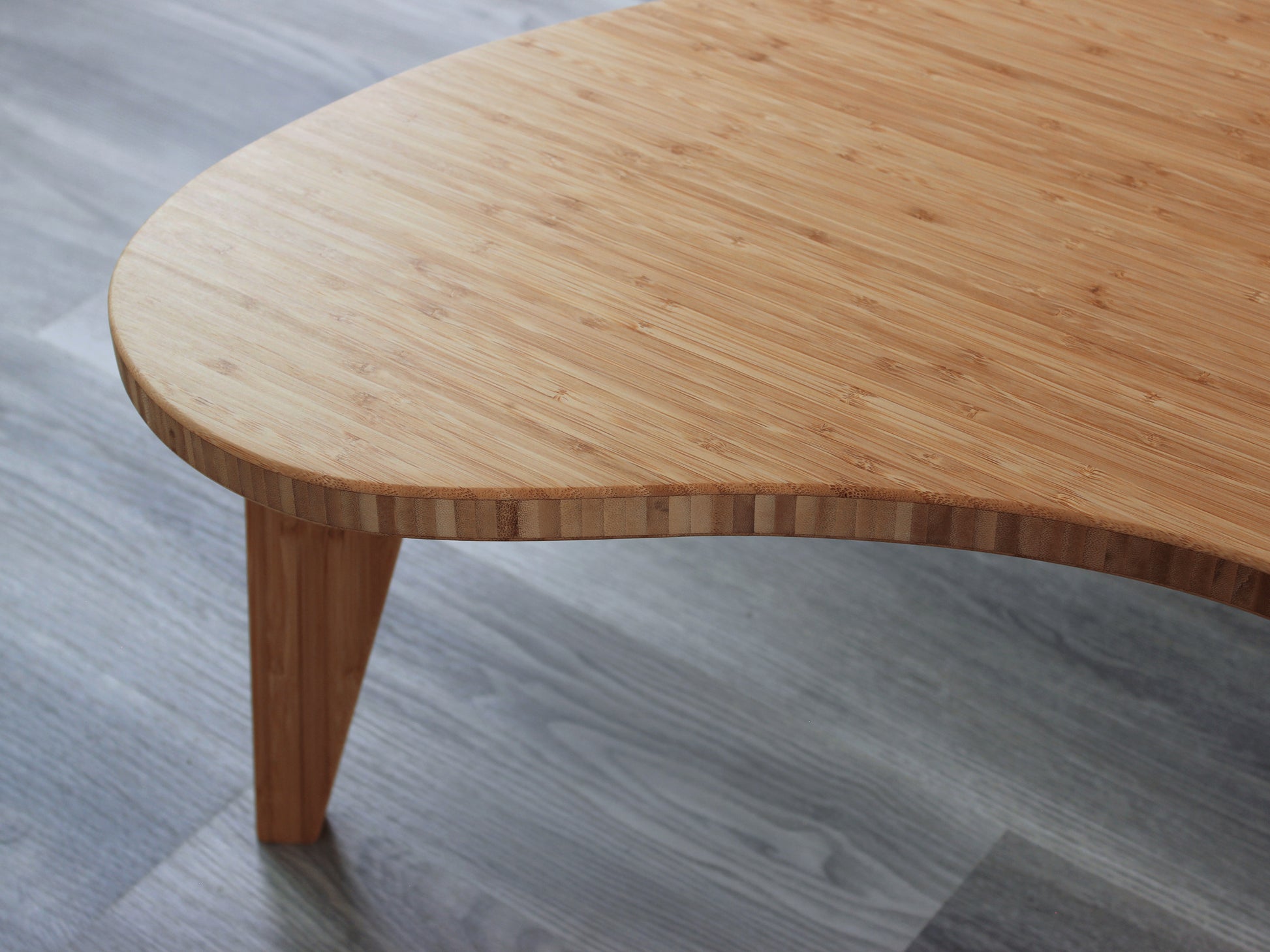 A kidney-shaped natural bamboo table, overhead view. Grey flooring with a white background. 

mid century modern low table
midcentury modern coffee table
floor table
japan coffee table
japan furniture
japan table
kidney coffee table 
bamboo low table
