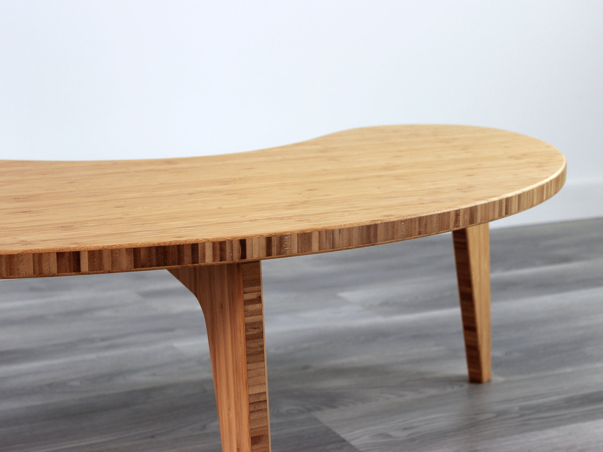 A kidney-shaped natural bamboo table. Grey flooring with a white background. 

mid century modern low table
midcentury modern coffee table
floor table
japan coffee table
japan furniture
japan table
kidney coffee table 
bamboo low table