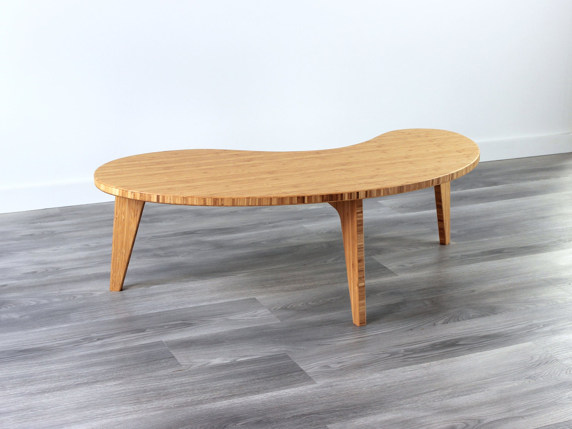 A kidney-shaped natural bamboo table. Grey flooring with a white background. 

mid century modern low table
midcentury modern coffee table
floor table
japan coffee table
japan furniture
japan table
kidney coffee table 
bamboo low table
