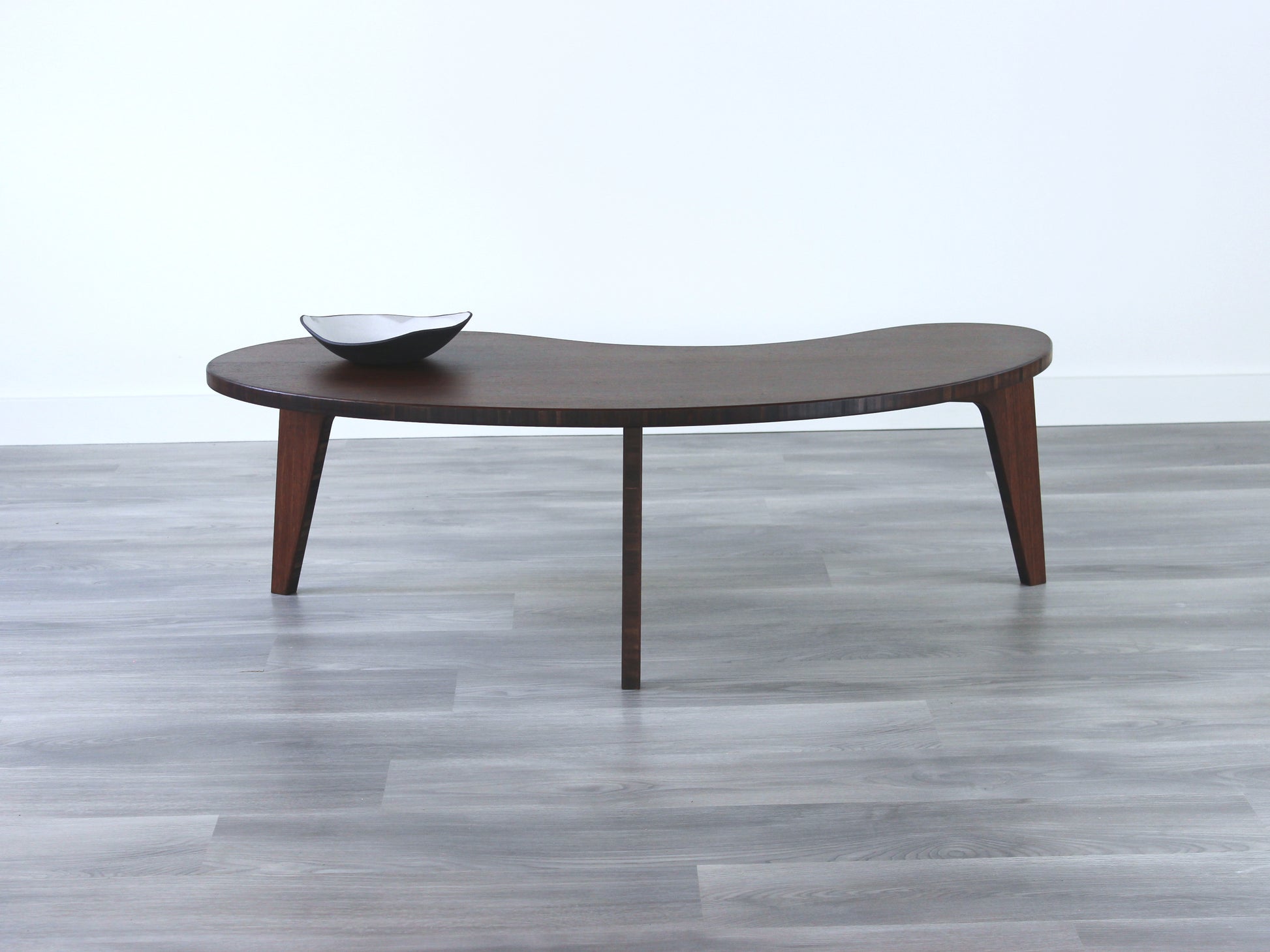 A kidney-shaped walnut bamboo table, featuring a small black and white pottery vessel placed on top. Grey flooring with a white background. 

mid century modern low table
midcentury modern coffee table
floor table
japan coffee table
japan furniture
japan table
kidney coffee table 
bamboo low table