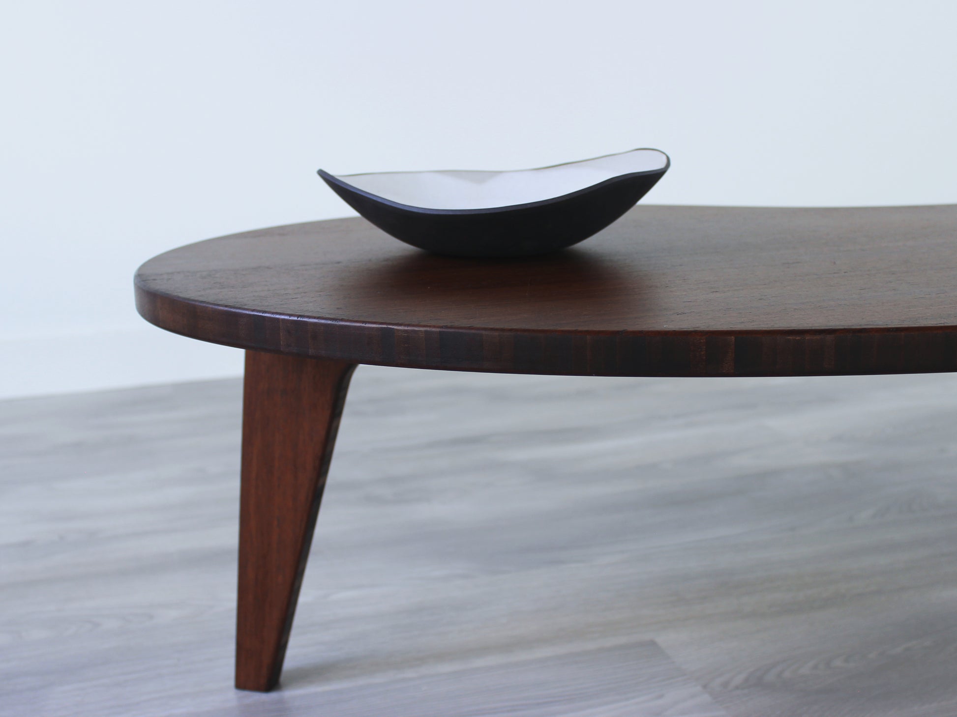 A kidney-shaped walnut bamboo table, featuring a small black and white pottery vessel placed on top. Grey flooring with a white background. 

mid century modern low table
midcentury modern coffee table
floor table
japan coffee table
japan furniture
japan table
kidney coffee table 
bamboo low table