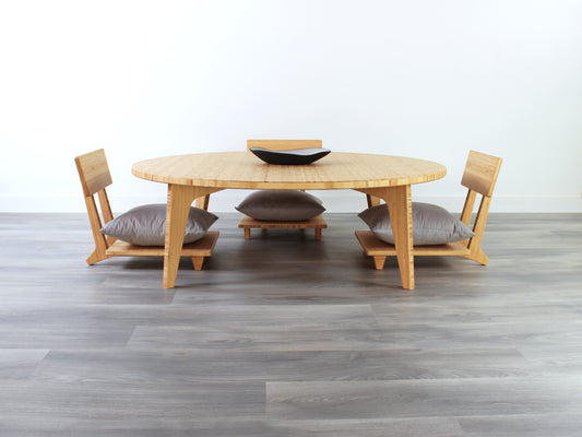 Large Circle Low Table with a natural bamboo finish and midcentury modern design. Three Floor Chair Comfort with grey pillows are set at the table. Small black pottery vessel placed on table top. 

Japandi, minimalist, mid-century, Japanese inspired, modern, contemporary, clean lines, organic design, sustainable bamboo, renewable bamboo, solid bamboo, eco-friendly furniture, natural materials, natural-based finish