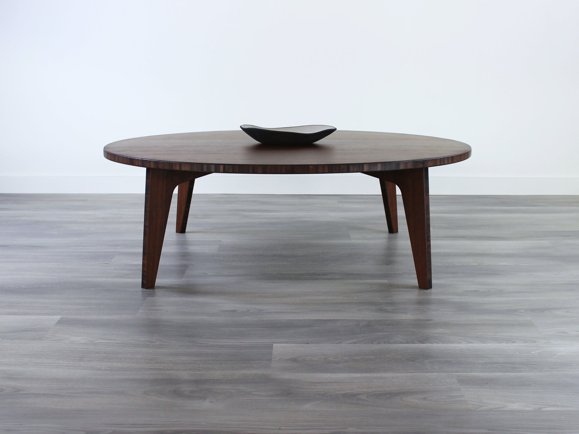 A round, walnut-colored bamboo table with a flat surface and curved legs on a gray floor, accompanied by a single black bowl.

Square low table 
japanese furniture
japanese low table
low coffee table
low dining table
low table
mid century
minimalist
minimalist table
modern
chabudai
kotatsu
large coffee table
