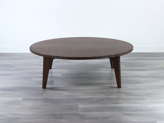 A round, walnut-colored bamboo table with a flat surface and curved legs on a gray floor.

Square low table 
japanese furniture
japanese low table
low coffee table
low dining table
low table
mid century
minimalist
minimalist table
modern
chabudai
kotatsu
large coffee table
