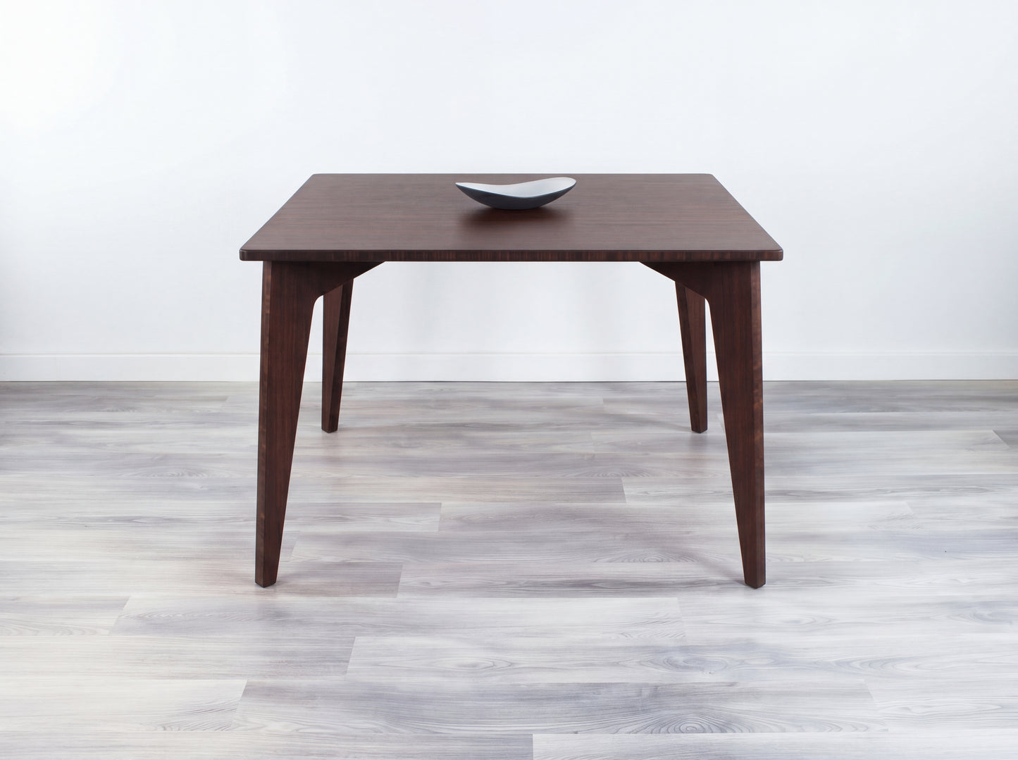 Bamboo table with a white wall and gray floor in the background