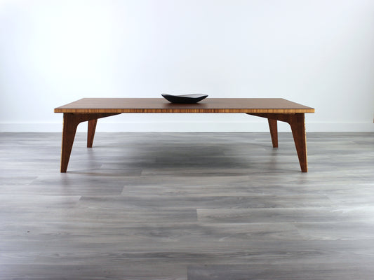 A large rectangular low table made of bamboo with a chestnut finish, placed on a grey floor, designed for multi-functional use in living spaces. A small black pottery vessel set on the table top. 

japanese furniture
japanese low table
low coffee table
low dining table
low table
mid century
minimalist
minimalist table
modern