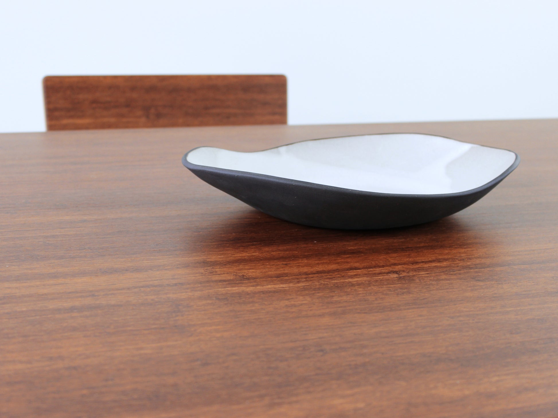 A large rectangular low table made of bamboo with a chestnut finish, placed on a grey floor with a white background. A black pottery vessel set on top of the table top. 

japanese furniture
japanese low table
low coffee table
low dining table
low table
mid century
minimalist
minimalist table
modern