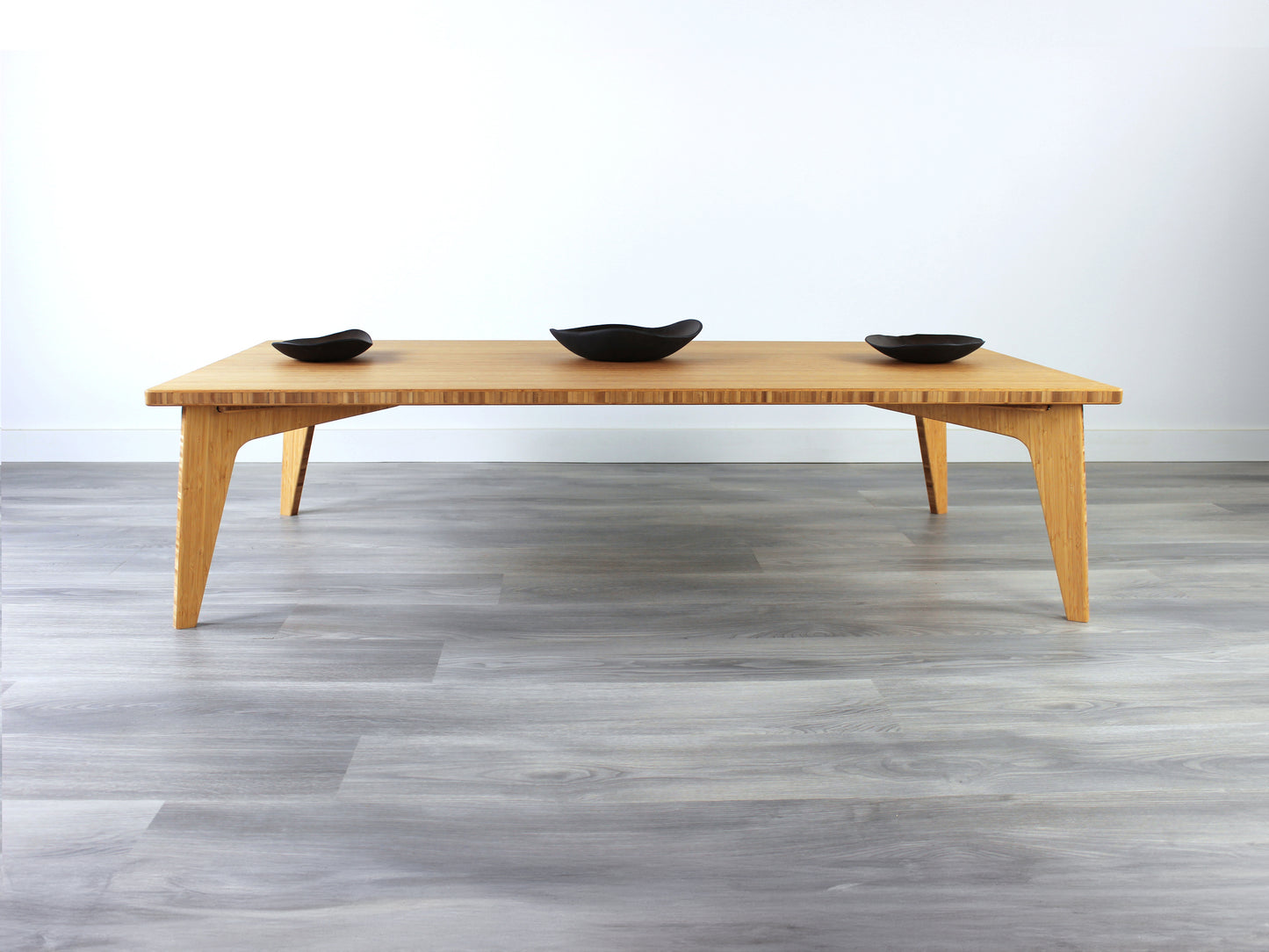 A rectangular low table made of bamboo with a natural finish, placed on a grey floor, designed for multi-functional use in living spaces. Three small black pottery vessels on the table top.

japanese furniture
japanese low table
low coffee table
low dining table
low table
mid century
minimalist
minimalist table
modern
floor dining table
floor table
japan coffee table
