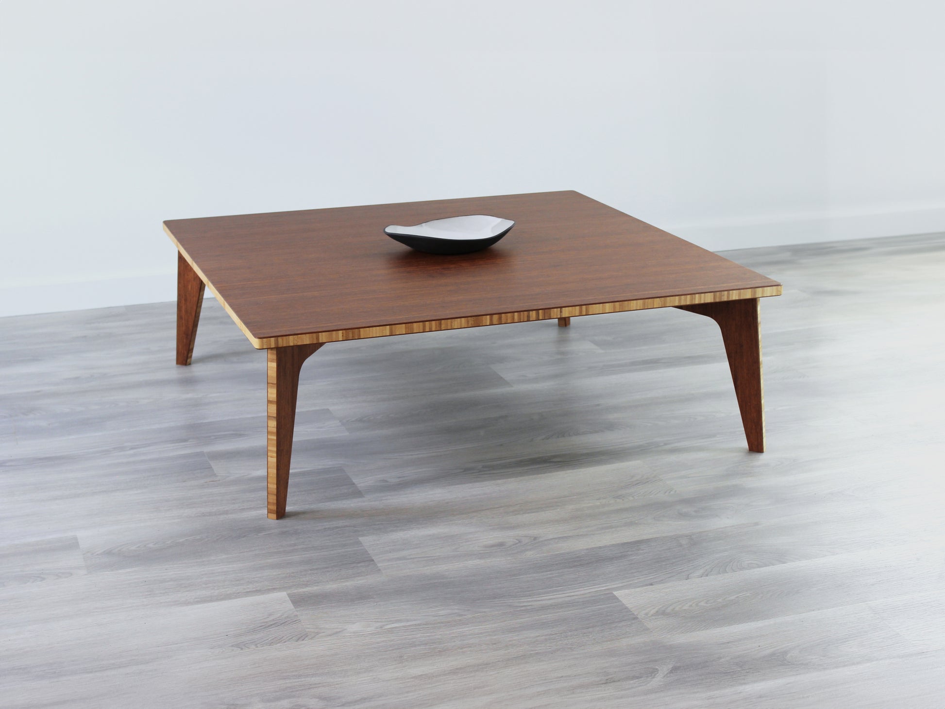 Large Square Low Table with a chestnut bamboo finish and midcentury modern design. Small black pottery vessel placed on table top. 

Japandi, minimalist, mid-century, Japanese inspired, modern, contemporary, clean lines, organic design, sustainable bamboo, renewable bamboo, solid bamboo, eco-friendly furniture, natural materials, natural-based finish