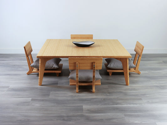 Large Square Low Table with a natural bamboo finish and midcentury modern design. Four Floor Chair Comfort with grey pillows are set at the table. Small black pottery vessel placed on table top. 

Japandi, minimalist, mid-century, Japanese inspired, modern, contemporary, clean lines, organic design, sustainable bamboo, renewable bamboo, solid bamboo, eco-friendly furniture, natural materials, natural-based finish