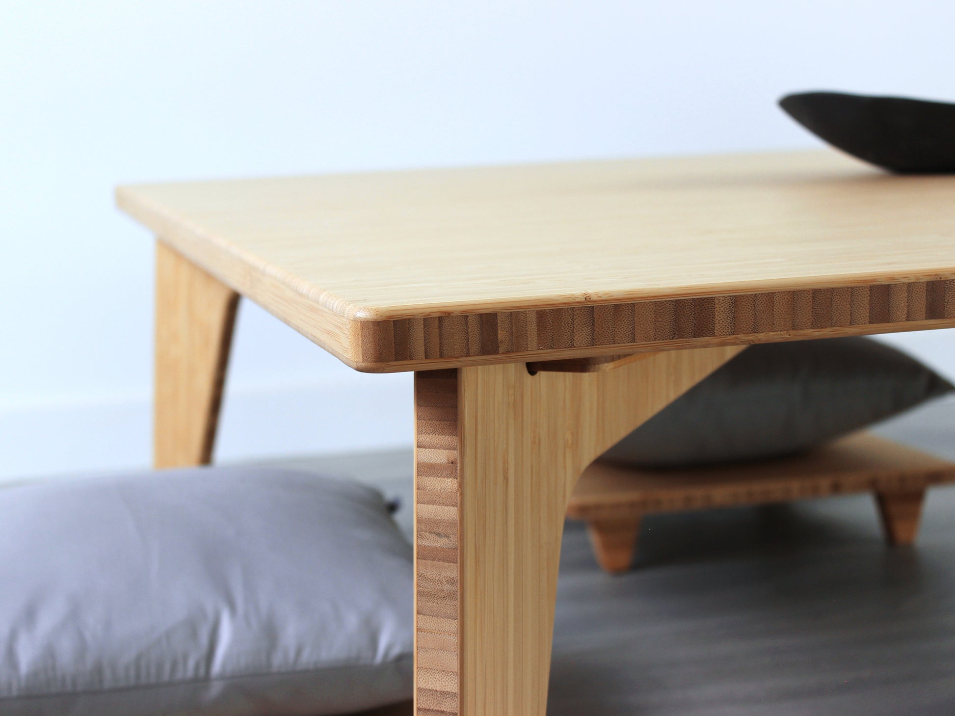 Large Square Low Table with a natural bamboo finish and midcentury modern design. Four Floor Chair Posture with grey pillows are set at the table. Small black pottery vessel placed on table top. 

Japandi, minimalist, mid-century, Japanese inspired, modern, contemporary, clean lines, organic design, sustainable bamboo, renewable bamboo, solid bamboo, eco-friendly furniture, natural materials, natural-based finish