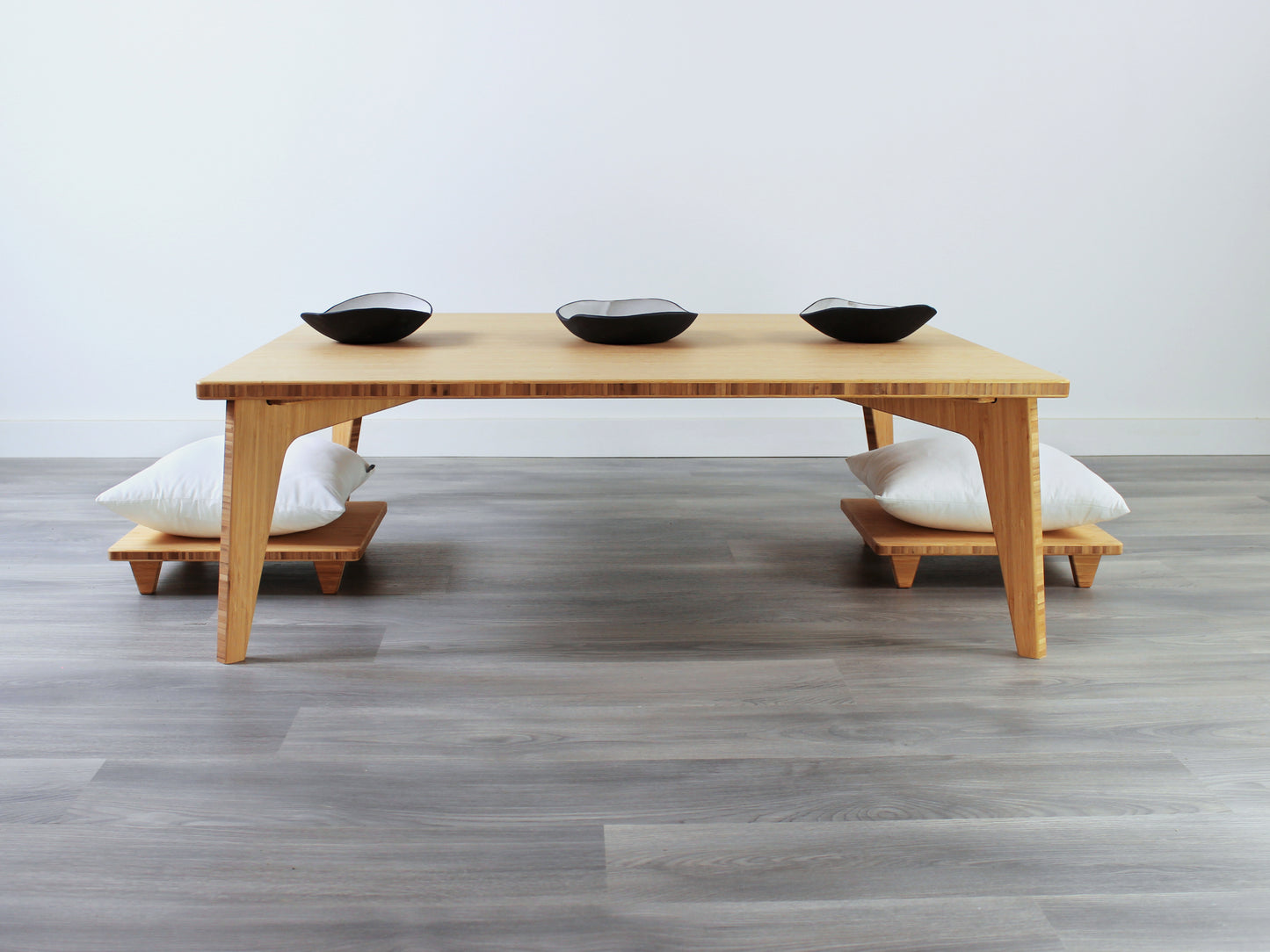 Large Square Low Table with a natural bamboo finish and midcentury modern design. Two Floor Chair Posture with white pillows are set at the table. Small black pottery vessels placed on table top. 

Japandi, minimalist, mid-century, Japanese inspired, modern, contemporary, clean lines, organic design, sustainable bamboo, renewable bamboo, solid bamboo, eco-friendly furniture, natural materials, natural-based finish
