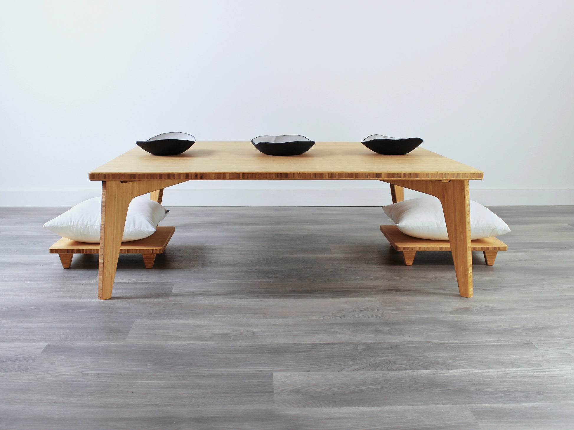 Large Square Low Table with a natural bamboo finish and midcentury modern design. Two Floor Chair Posture with white pillows are set at the table. Small black pottery vessels placed on table top. 

Japandi, minimalist, mid-century, Japanese inspired, modern, contemporary, clean lines, organic design, sustainable bamboo, renewable bamboo, solid bamboo, eco-friendly furniture, natural materials, natural-based finish