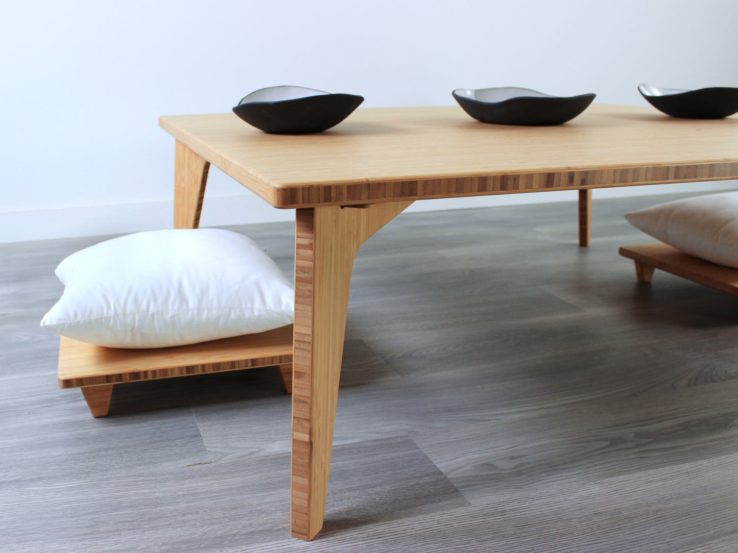 Large Square Low Table with a natural bamboo finish and midcentury modern design. Two Floor Chair Posture with grey pillows are set at the table. Small black pottery vessels placed on table top. 

Japandi, minimalist, mid-century, Japanese inspired, modern, contemporary, clean lines, organic design, sustainable bamboo, renewable bamboo, solid bamboo, eco-friendly furniture, natural materials, natural-based finish