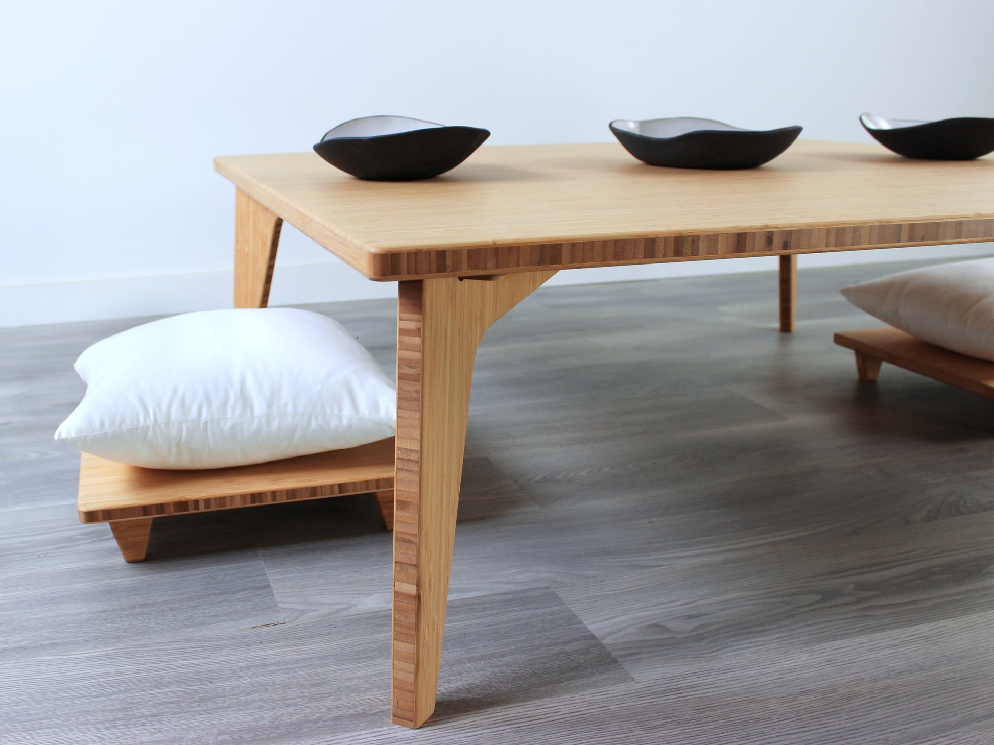 Large Square Low Table with a natural bamboo finish and midcentury modern design. Two Floor Chair Posture with grey pillows are set at the table. Small black pottery vessels placed on table top. 

Japandi, minimalist, mid-century, Japanese inspired, modern, contemporary, clean lines, organic design, sustainable bamboo, renewable bamboo, solid bamboo, eco-friendly furniture, natural materials, natural-based finish